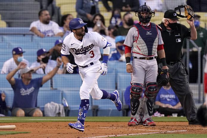 Chris Taylor, de los Dodgers de Los Ángeles, a la izquierda, corre a primera tras conectar un jonrón de tres carreras, mientras el receptor de los Nationals de Washington, Yan Gomes, observa.