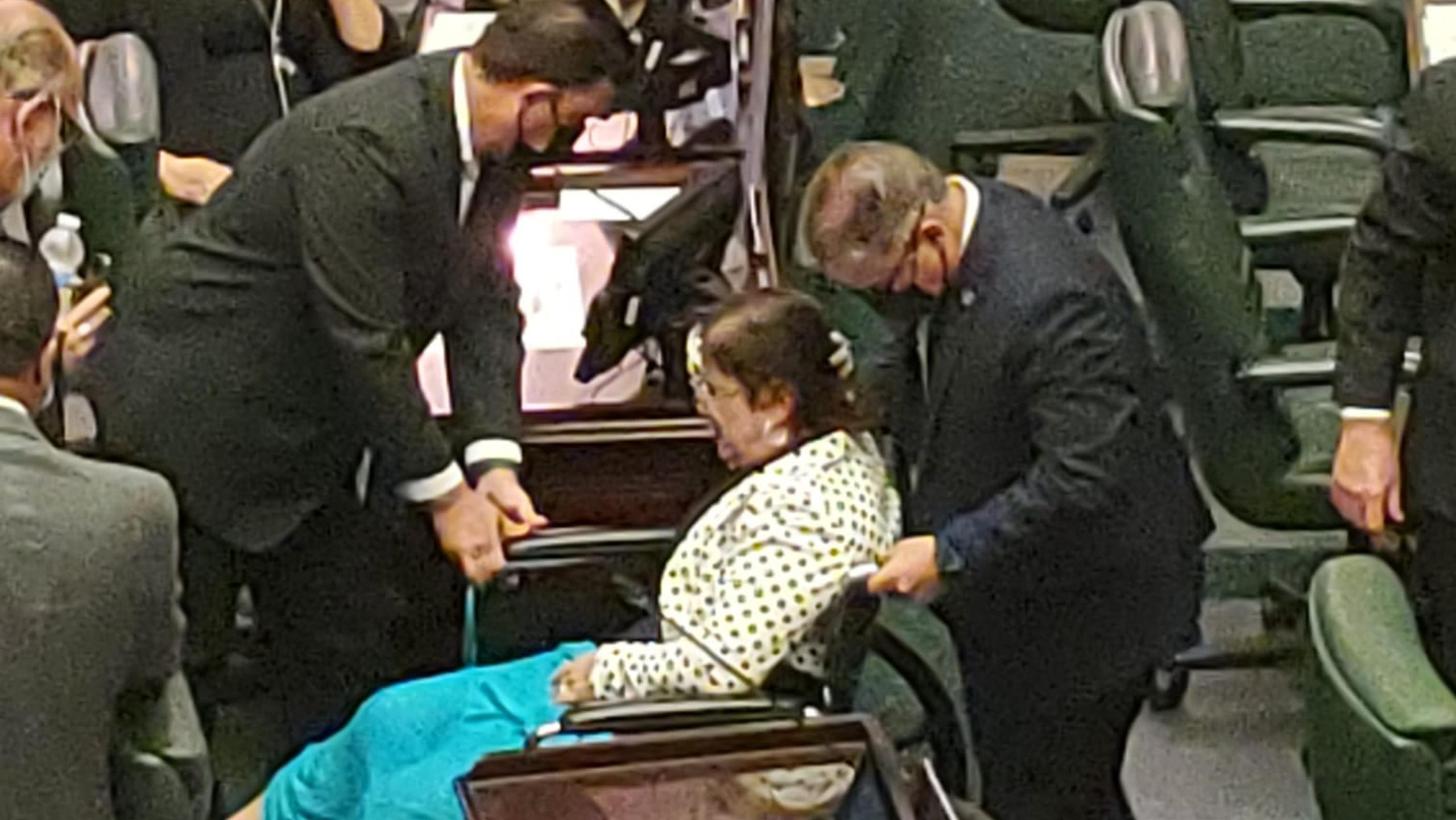 La representante Wanda del Valle fue sacada en silla de ruedas del hemiciclo ayer, tras desmayarse.