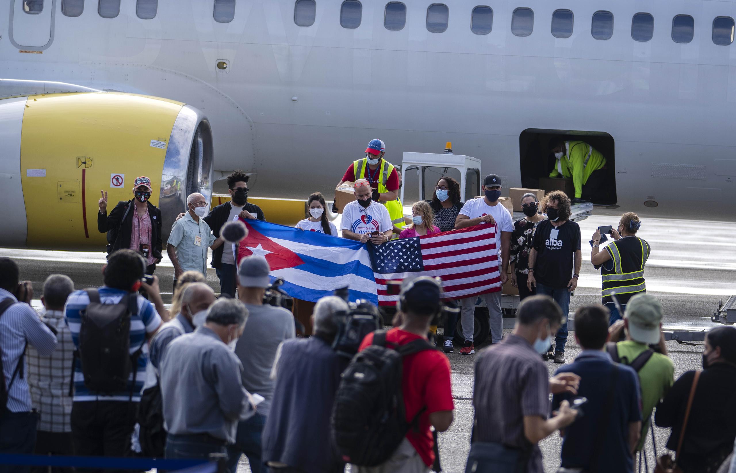 Representantes de varias ONG posaron con banderas de Estados Unidos y Cuba frente a un avión que trajo 10 toneladas de ayuda alimentaria.