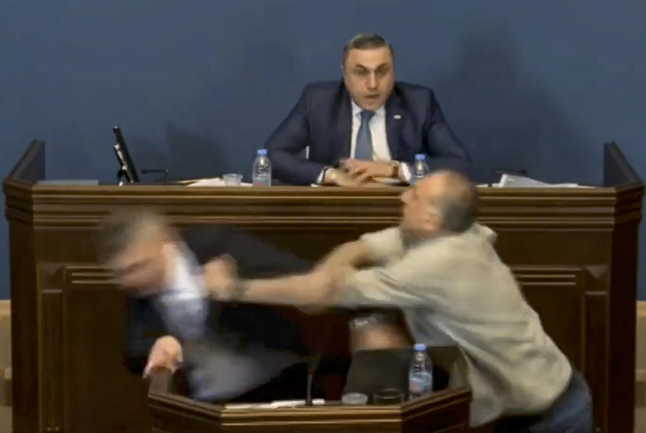 Una imagen fija tomada de un vídeo transmitido en vivo del Parlamento de Georgia muestra al líder de la facción parlamentaria del partido gobernante Sueño Georgiano, Mamuka Mdinaradze (L), siendo golpeado en la cara por la oposición El diputado Aleko Elisashvili.