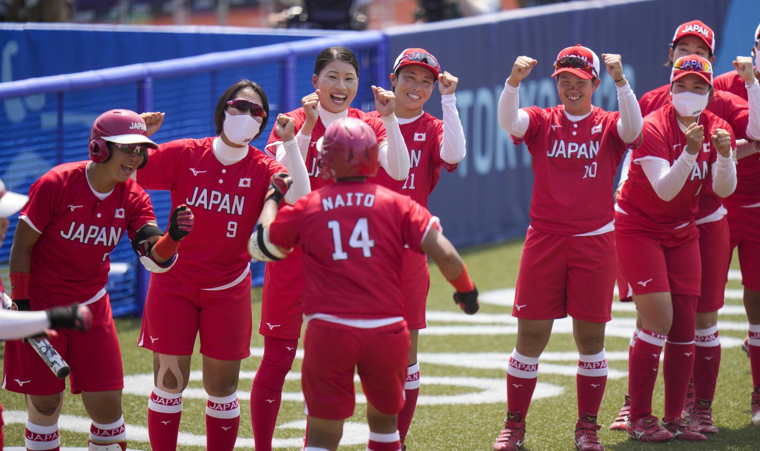 Minori Naito (14), de Japón, celebra con sus compañeras luego de anotar una carrera durante el encuentro inaugural del sóftbol femenino ante Australia.
