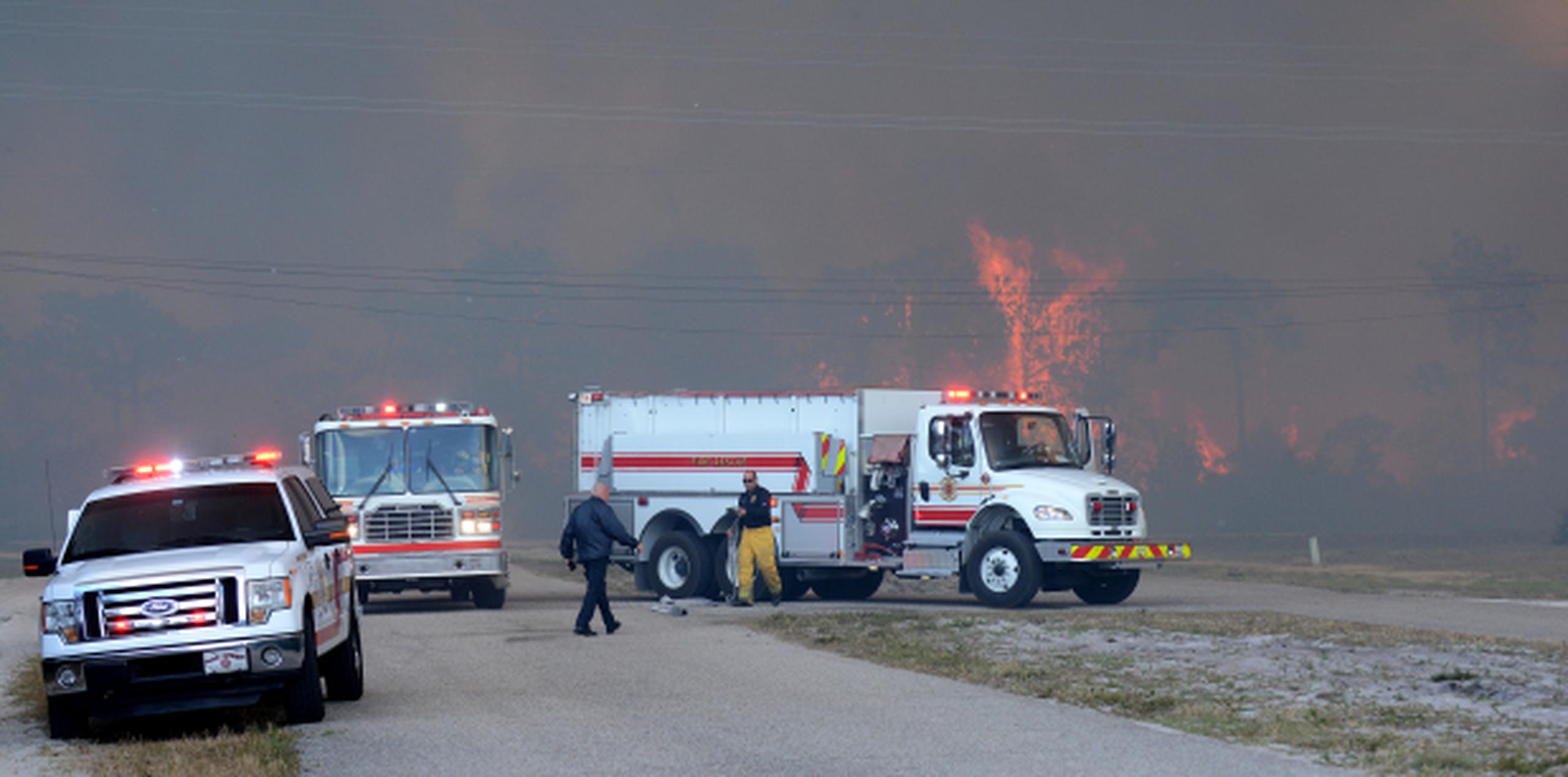 Bomberos trabajan rodeados de una intensa humareda en Indian Lake Estates, en el Condado de Polk, Florida. (EFE / Pol County Fire Rescue)