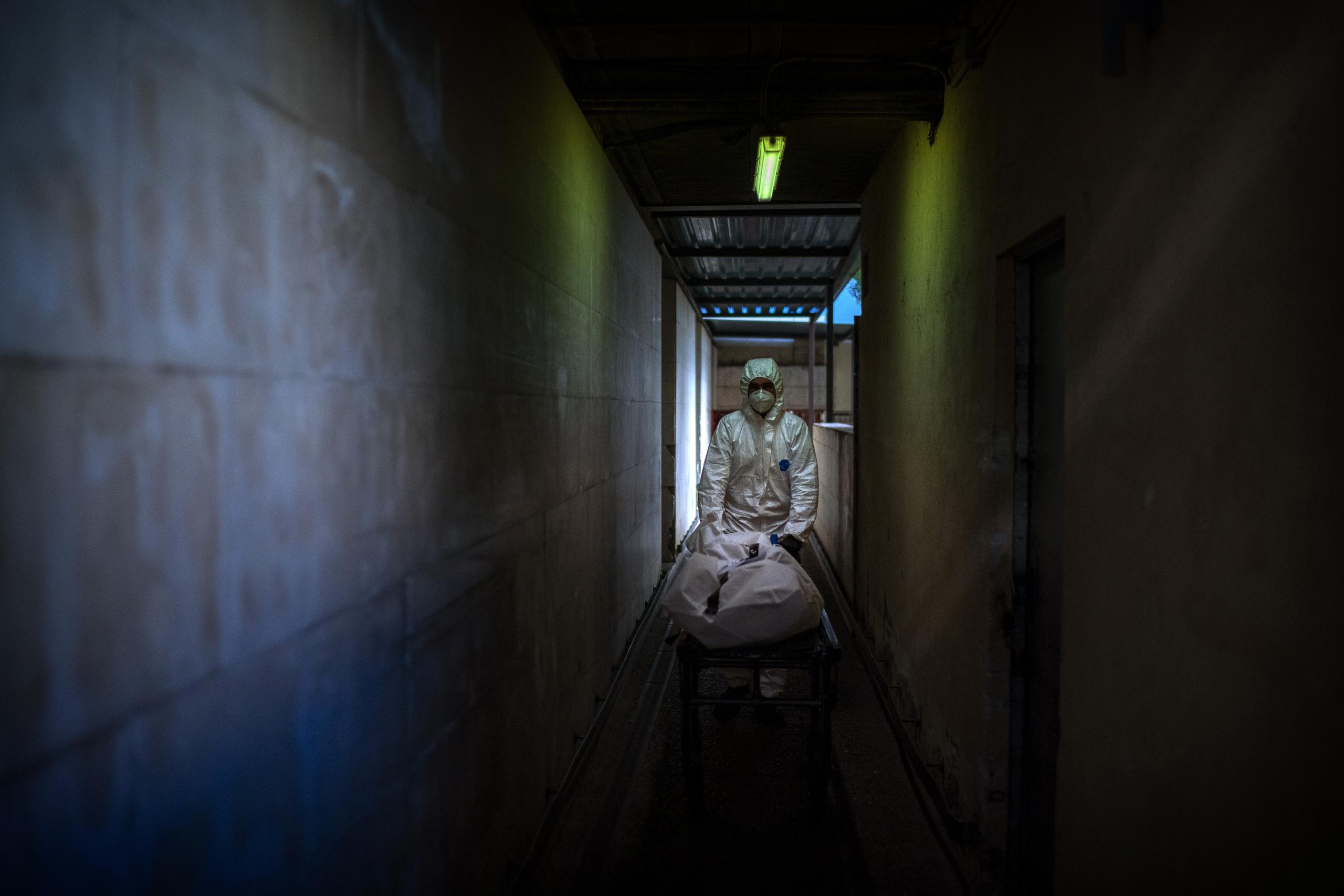 Un empleado de una funeraria traslada el cuerpo de una víctima del coronavirus en una camilla a la morgue de un hospital, en Barcelona.