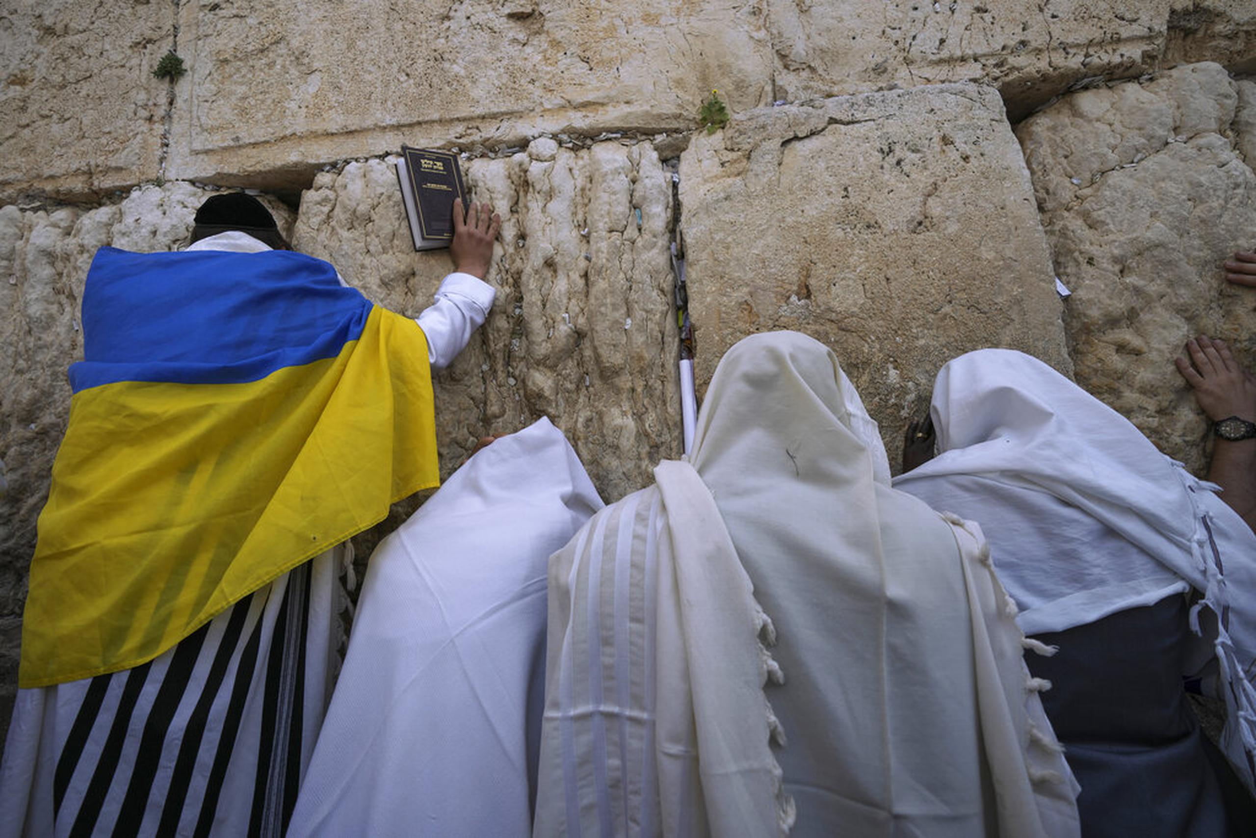 Un judío ultraortodoxo envuelto con una bandera ucraniana antes de la bendición sacerdotal, durante la festividad judía de la Pascua, en el Muro Occidental, el lugar más sagrado donde los judíos pueden orar en la Ciudad Vieja de Jerusalén, el 18 de abril de 2022.