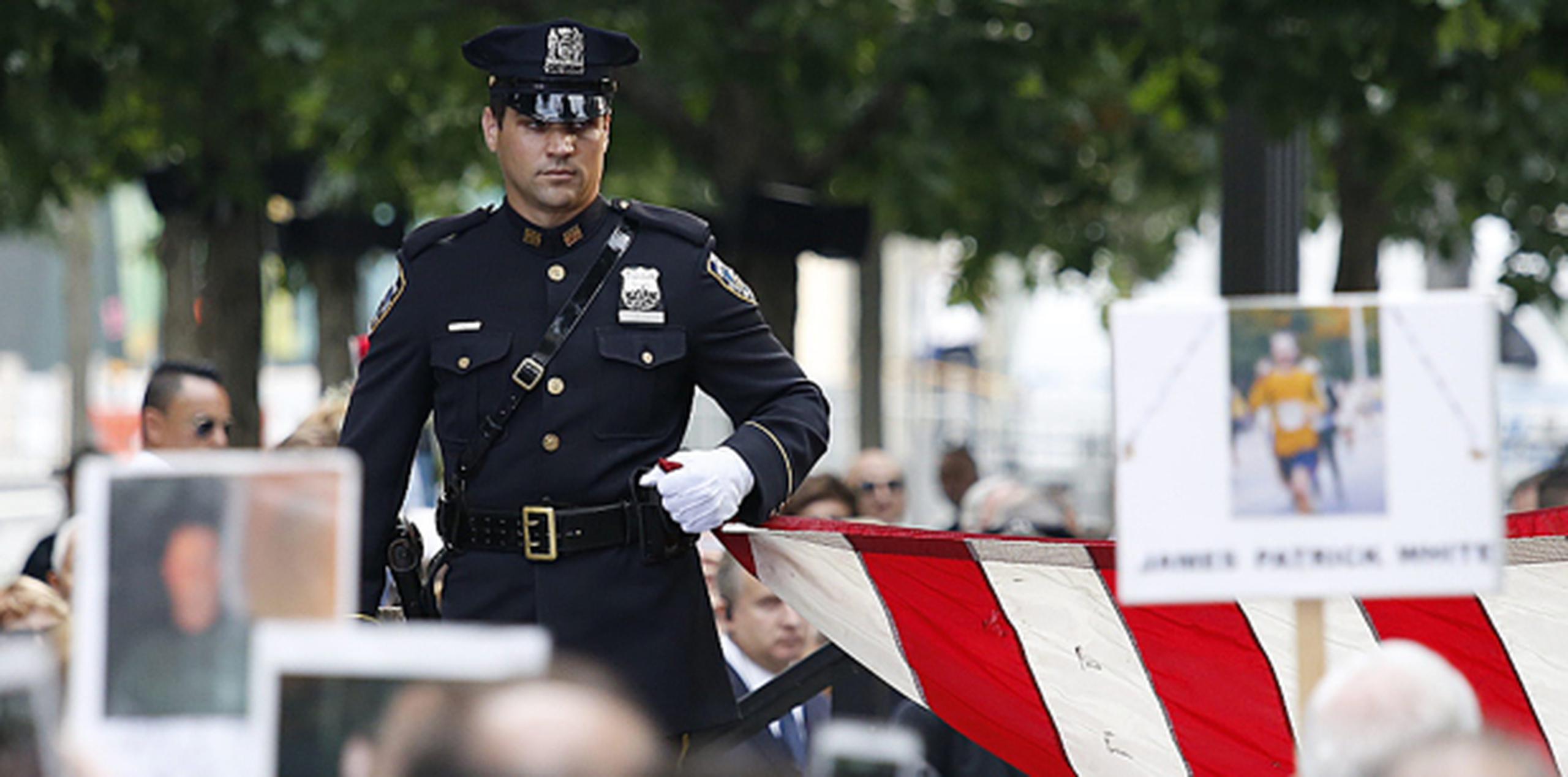 Un policía con una bandera de Estados Unidos en la ceremonia en Nueva York del decimoquinto aniversario de los ataques terroristas del 11 de septiembre. (AP)