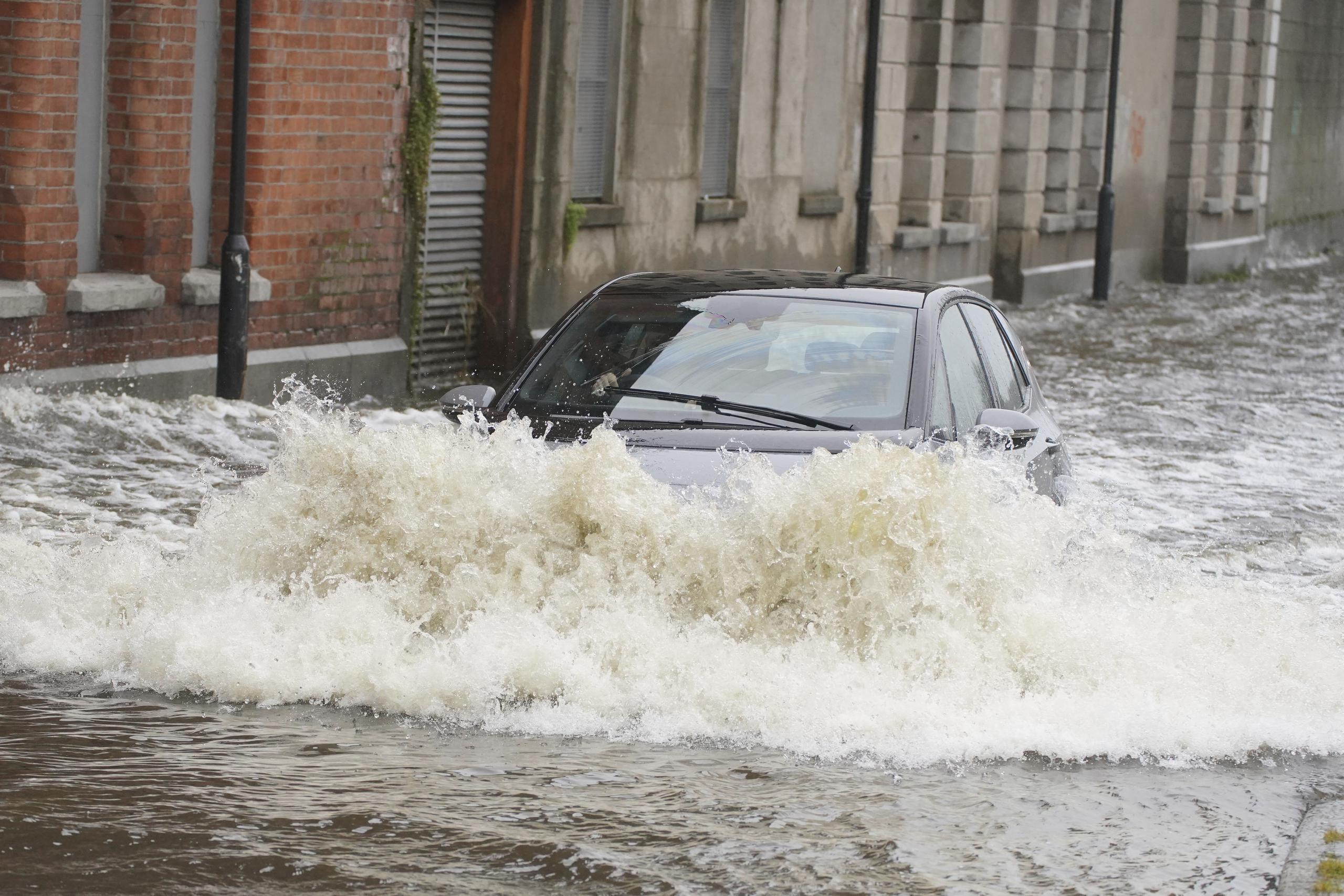 Un coche avanza por una calle anegada por el desbordamiento de un canal debido a las intensas lluvias en Newry Town, Co Down, el 1 de noviembre de 2023. (Brian Lawless/PA vía AP)