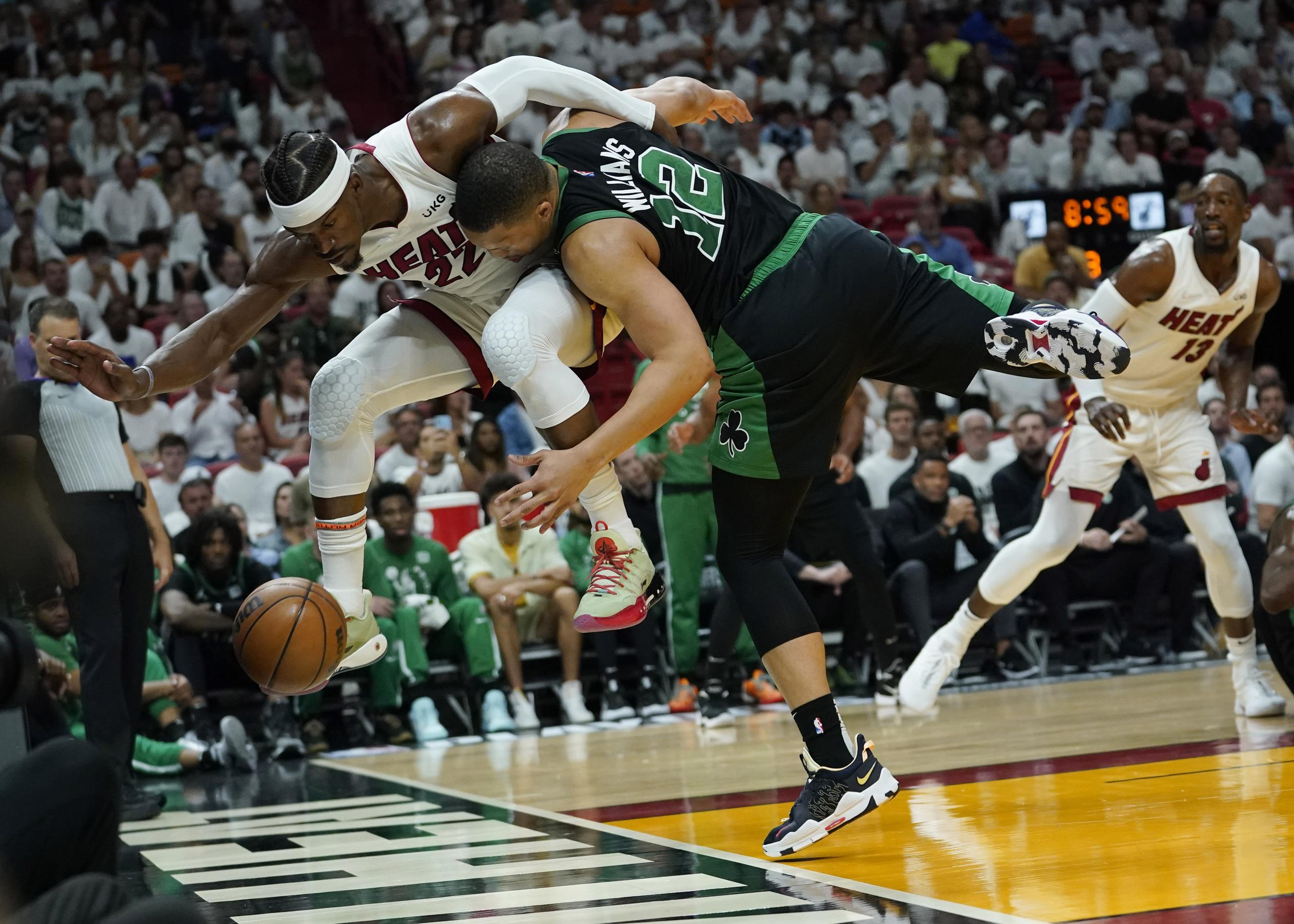 El delantero del Heat de Miami, Jimmy Butler y Grant Williams, de los Celtics, van ambos tras una bola suelta durante el desafío del miércoles en Miami.