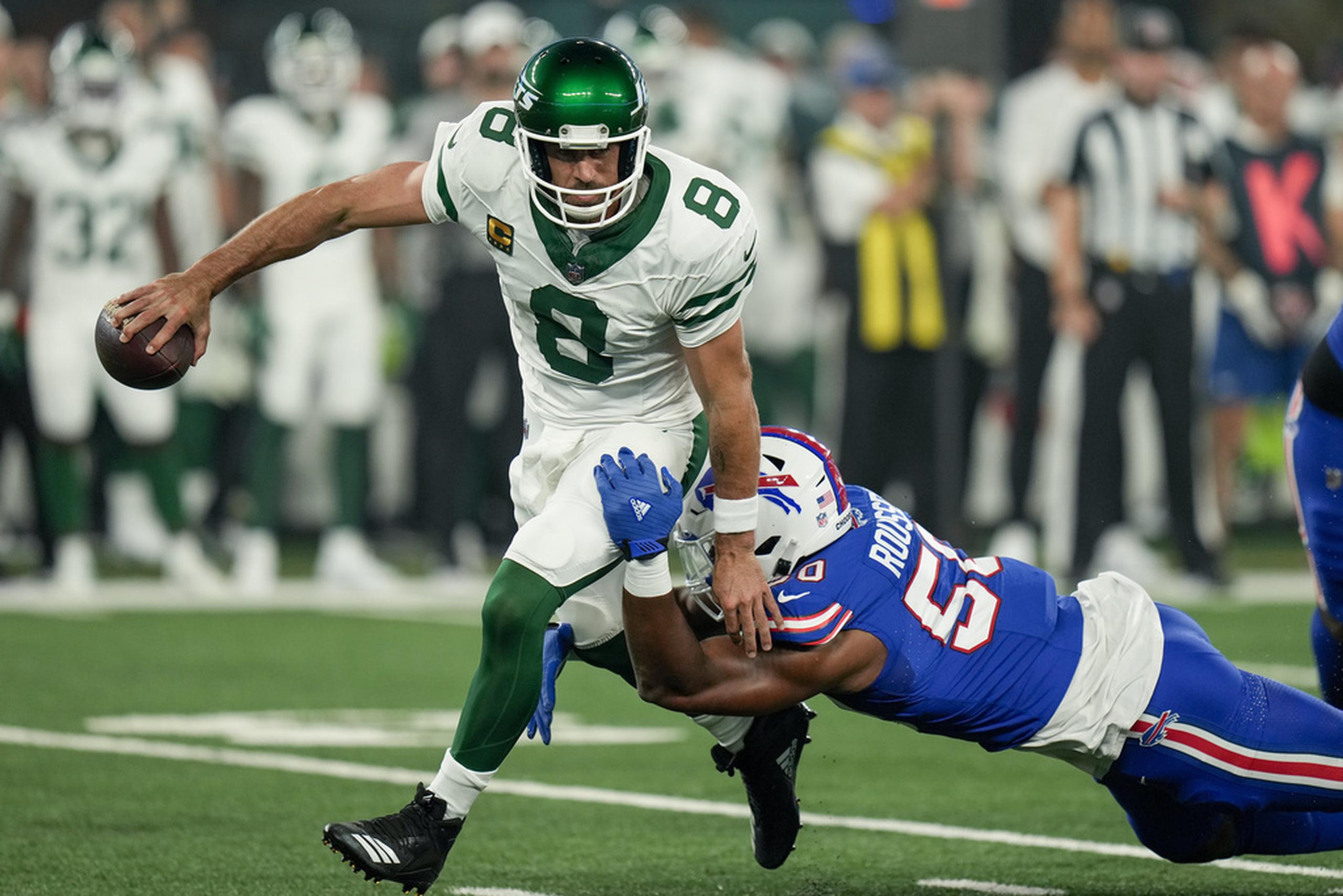 Aaron Rodgers, quarterback de los Jets de Nueva York, es derribado por Greg Rousseau, de los Bills de Buffalo.