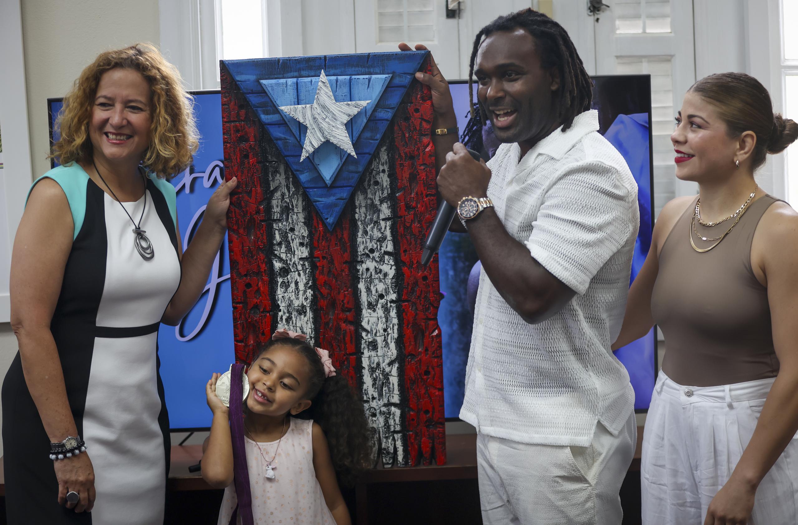 La presidenta del Comité Olímpico le entrega a Jaime Espinal un obra de la bandera de Puerto Rico.