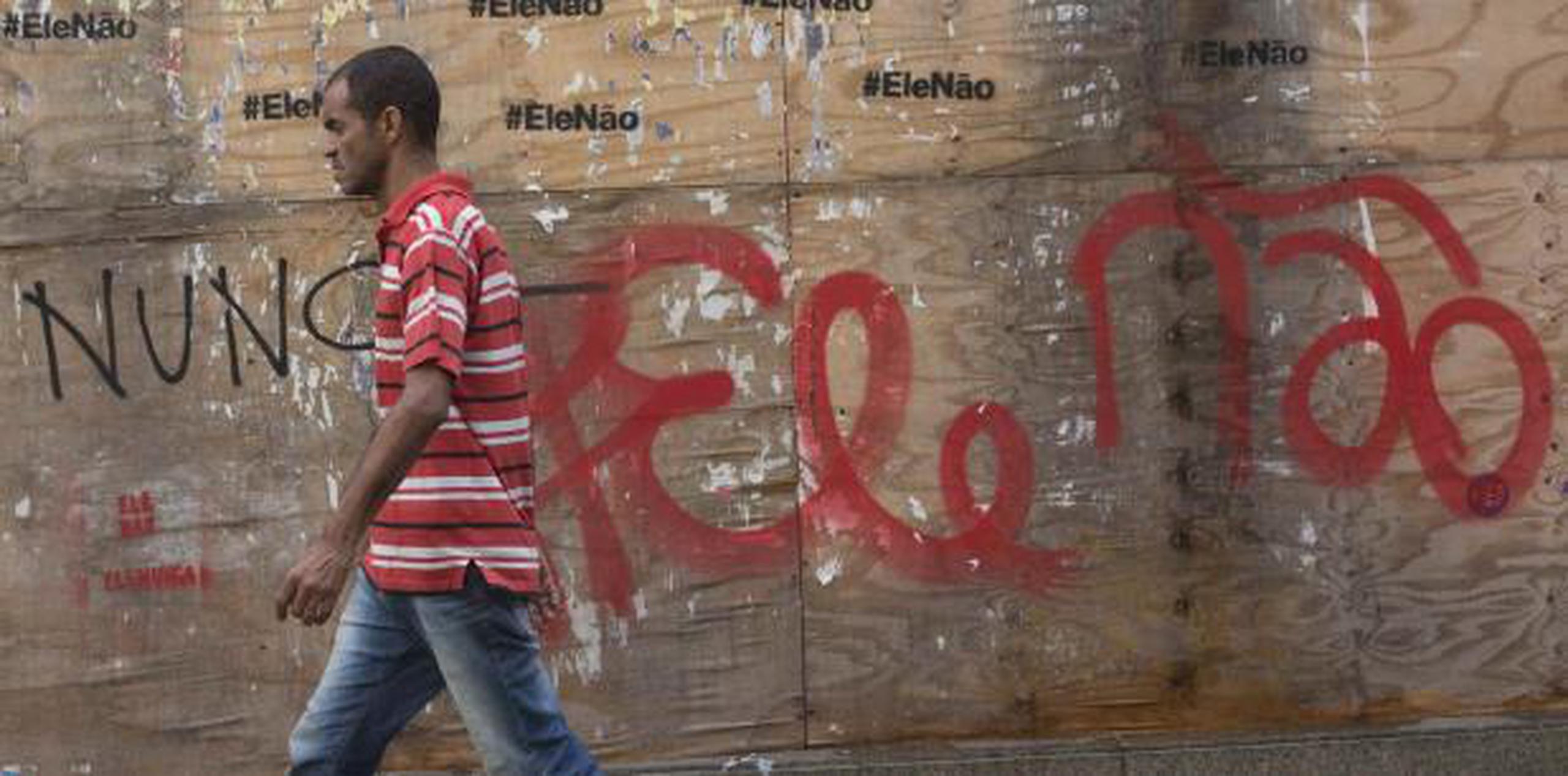 Un hombre pasa junto a un graffiti que dice en portugués: "No él" en Río de Janeiro, (AP)