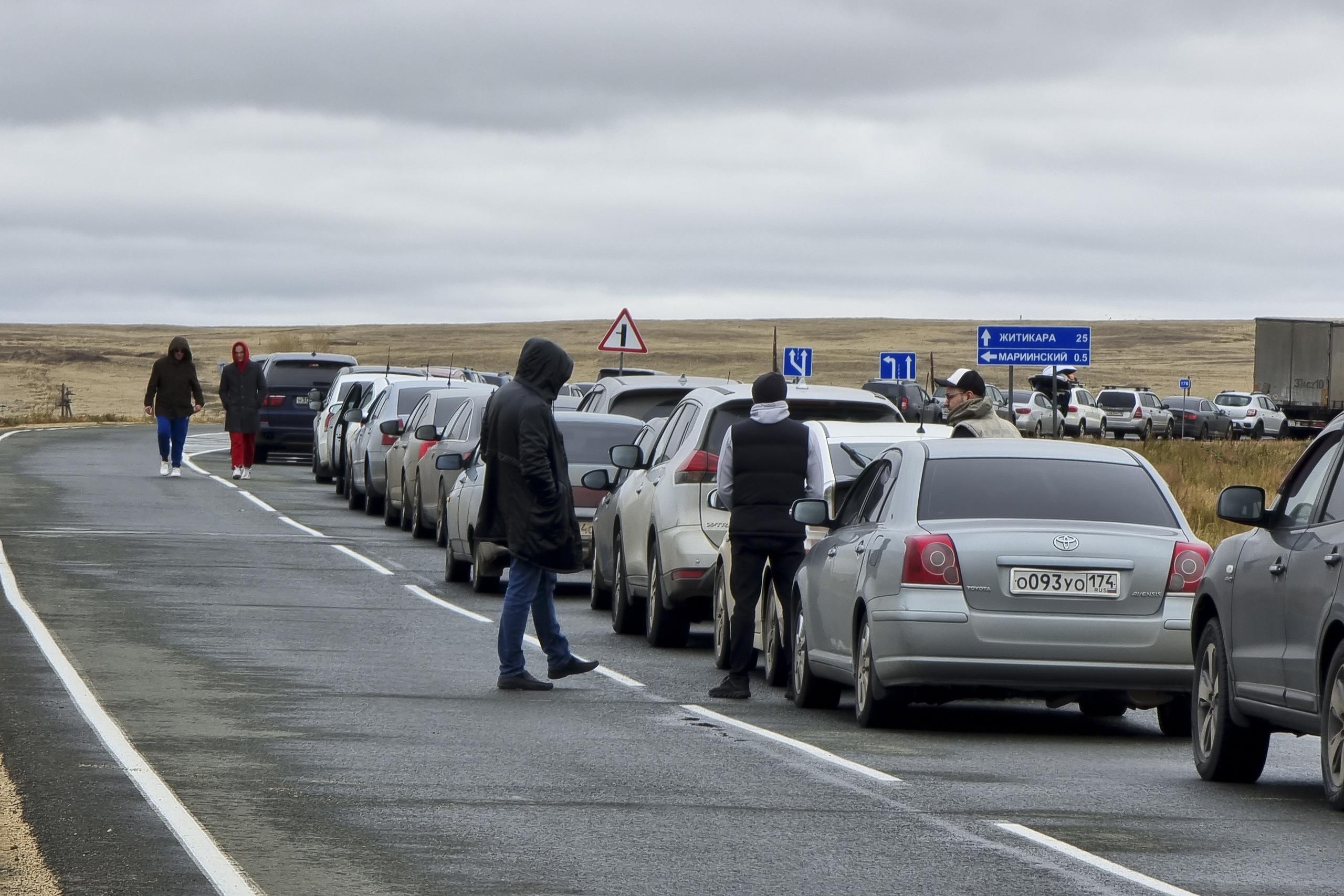 La gente camina junto a sus automóviles haciendo fila para cruzar la frontera con Kazajistán en el paso fronterizo de Mariinsky, a unos 400 kilómetros al sur de Chelyabinsk, Rusia, el martes 27 de septiembre de 2022.
