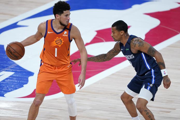 Devin Booker de los Suns de Phoenix intenta superar a Trey Burke de los Mavericks de Dallas durante el juego esta tarde.