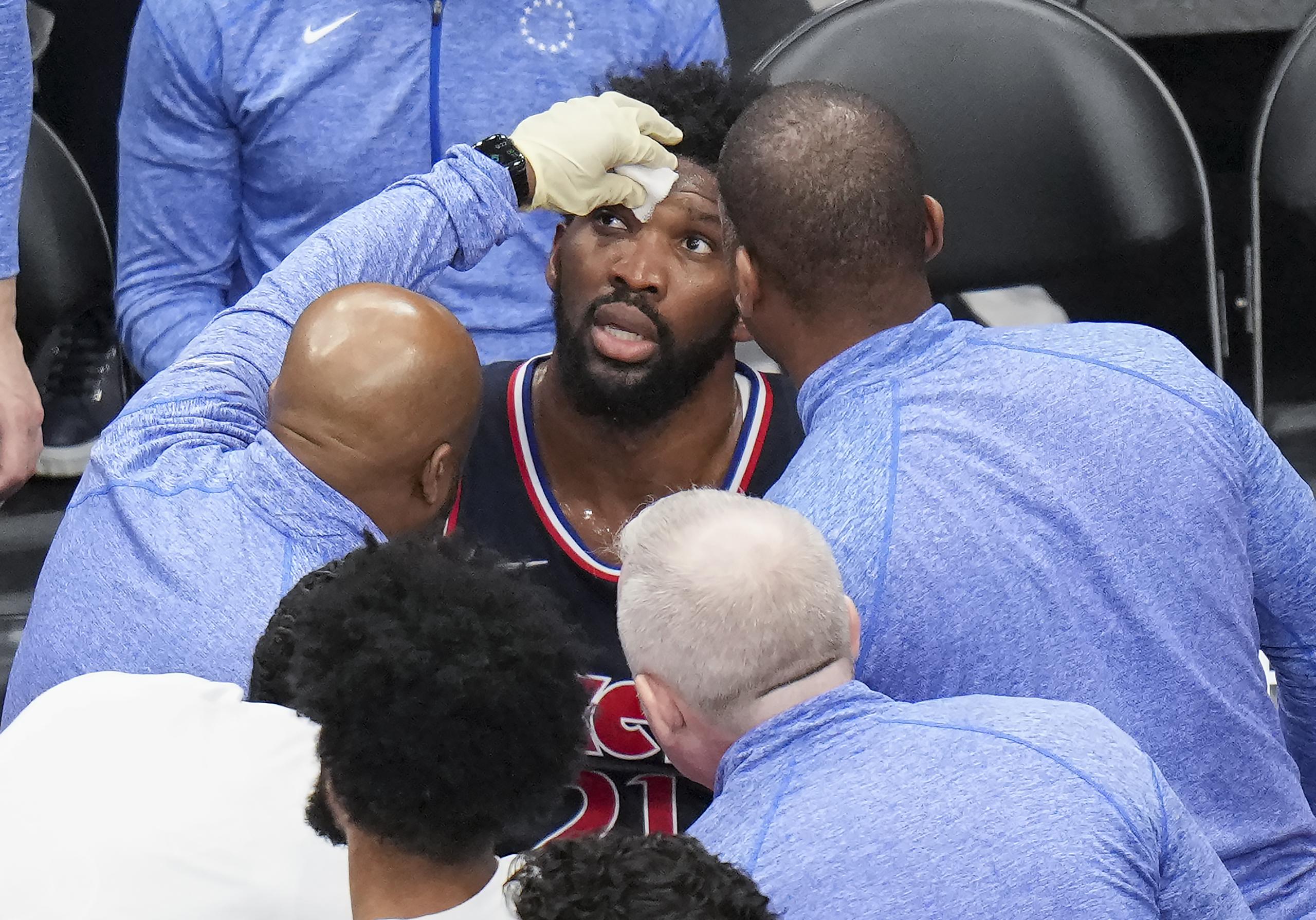 Joel Embiid recibe atención tras sufrir un golpe en el rostro durante el sexto partido de la serie de playoffs ante los Raptors de Toronto.
