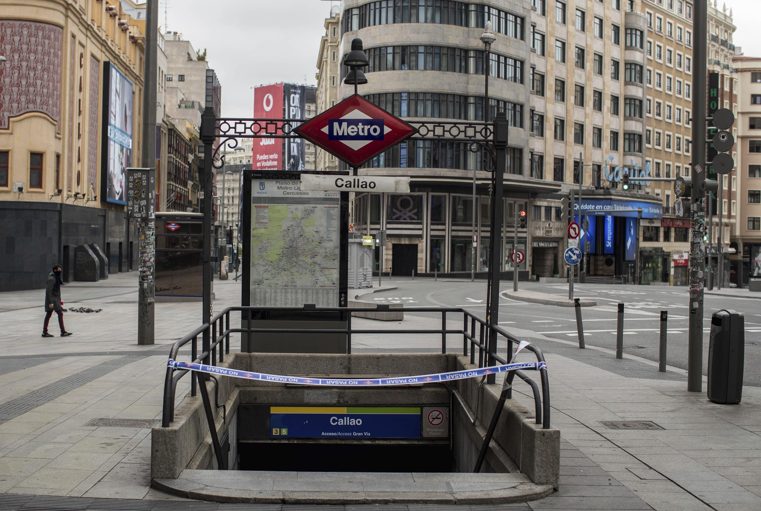 Un individuo camino pasa cerca de una estación del metro de Madrid que ha sido cerrado durante el confinamiento en España por el coronavirus.