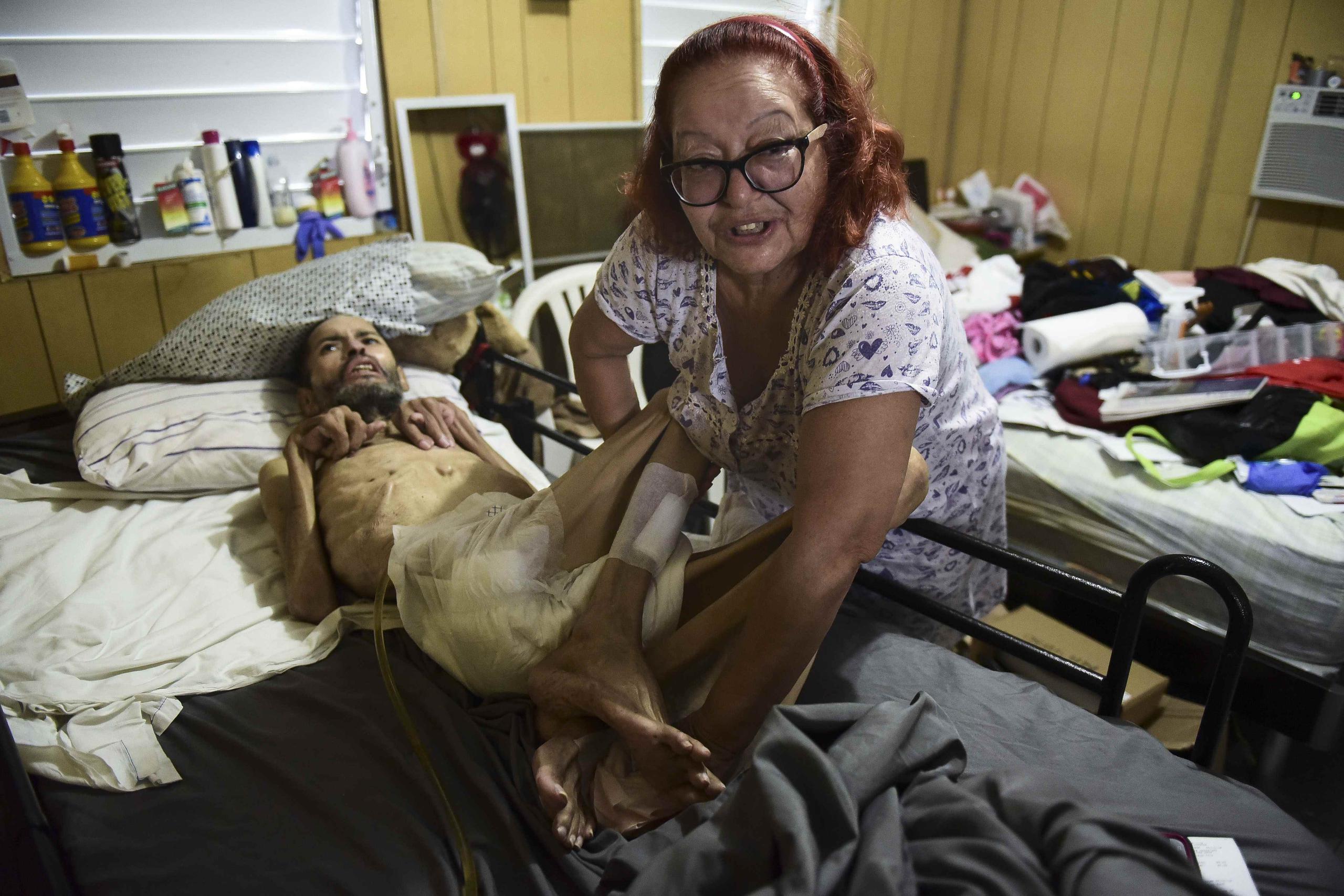 Rosa Rivera Martínez cuida de su esposo, Maximino Acosta Reyes, que está confinado a la cama. Ambos viven en una casa con el tejado dañado en la barriada Figueroa, en San Juan. (AP / Carlos Giusti)