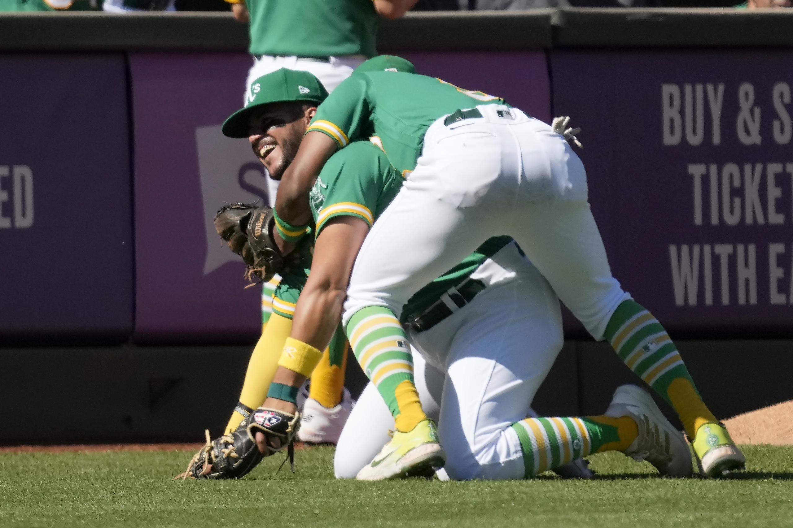 El antesalista puertorriqueño de los Athletics de Oakland, Vimael Machín, sonríe al ser abrazado por su compañero Tony Kemp luego de atrapar un batazo de foul de Eduardo Escobar, de los Mets de Nueva York.