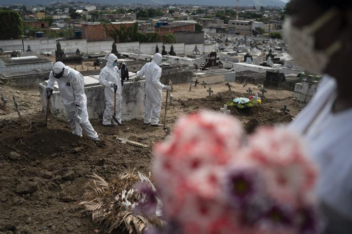 Trabajadores de un cementerio, vestidos con trajes de protección, cierran la tumba de Ana María, una ayudante de enfermería de 56 años que falleció a causa del coronavirus, en Río de Janeiro, Brasil.
