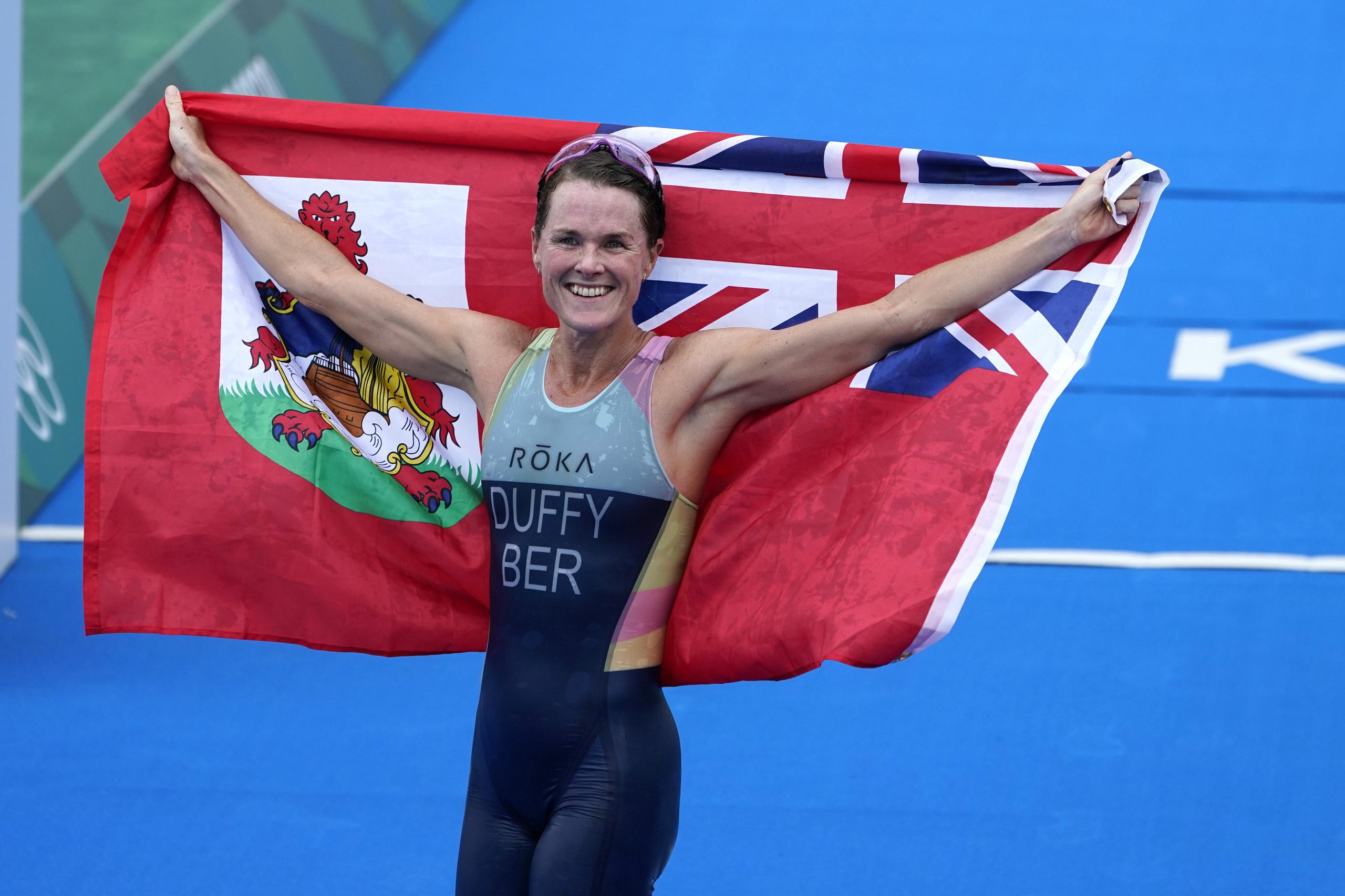 Flora Duffy, de Bermuda, muestra la bandera que representa luego de ganar el oro en el tríalo individual femenino de los Juegos de Tokio 2020.