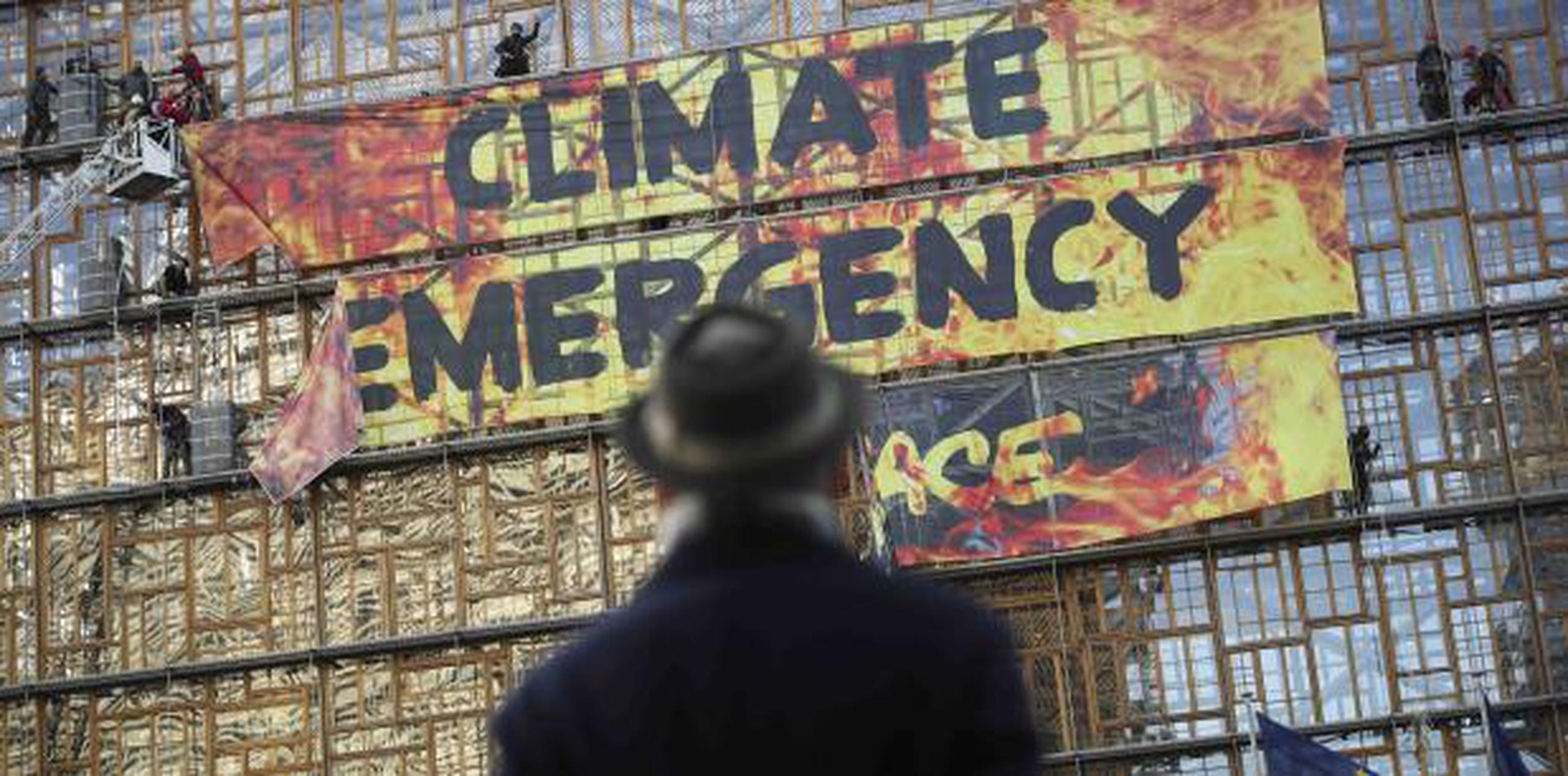 Un hombre observa una pancarta que denucia la inacción ante el cambio climático. (AP)