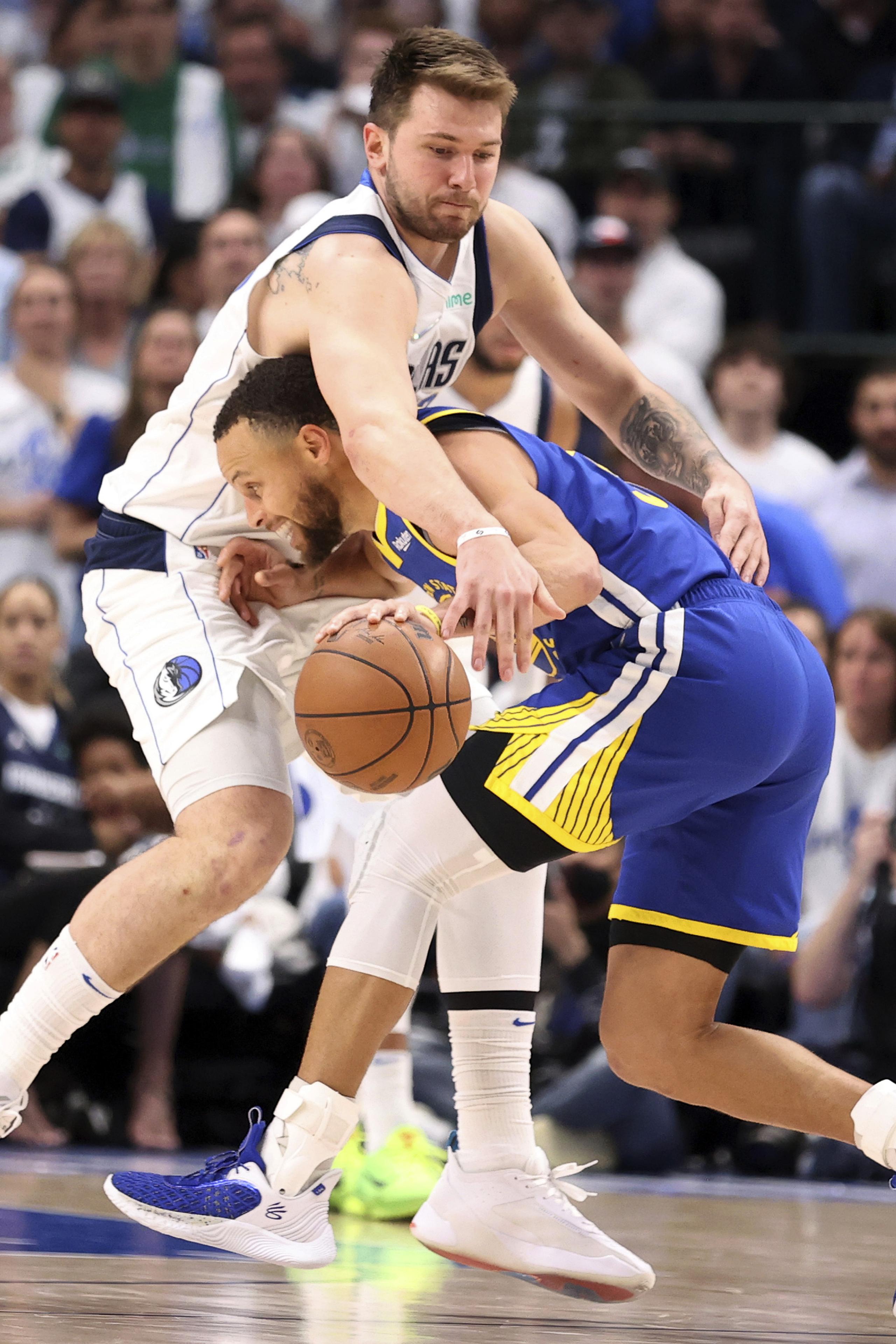 Luka Doncic, de los Mavericks de Dallas, intenta arrebatarle el balón al armador de los Warriors de Golden State, Stephen Curry, durante el encuentro del martes en Dallas.