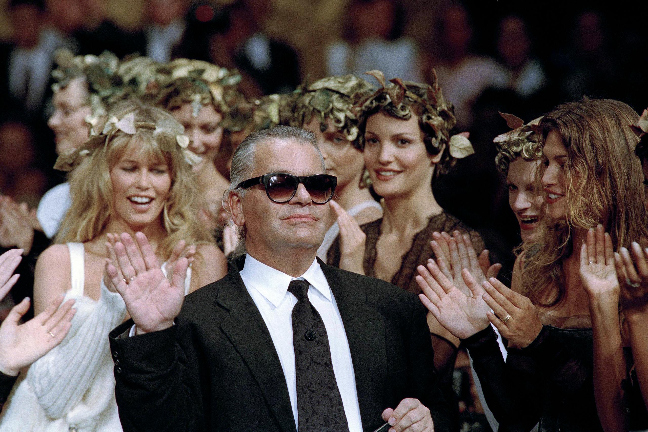 En esta foto de archivo, el diseñador de moda alemán Karl Lagerfeld agradece el aplauso de sus modelos al final del desfile que diseñó para la casa de moda francesa Chanel, para la colección de alta costura otoño-Invierno 1993-94 en París, el 20 de julio de 1993.