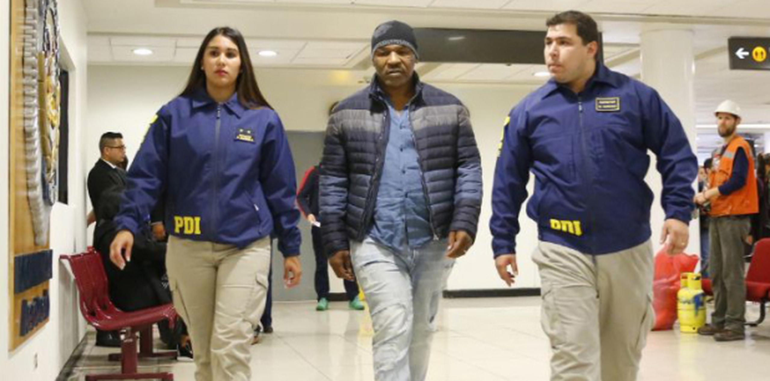 Miembros de la Policía de Investigación chilena escoltan a Mike Tyson tras su arribo al Aeropuerto Internacional de Santiago de Chile. (AP/Esteban Felix)
