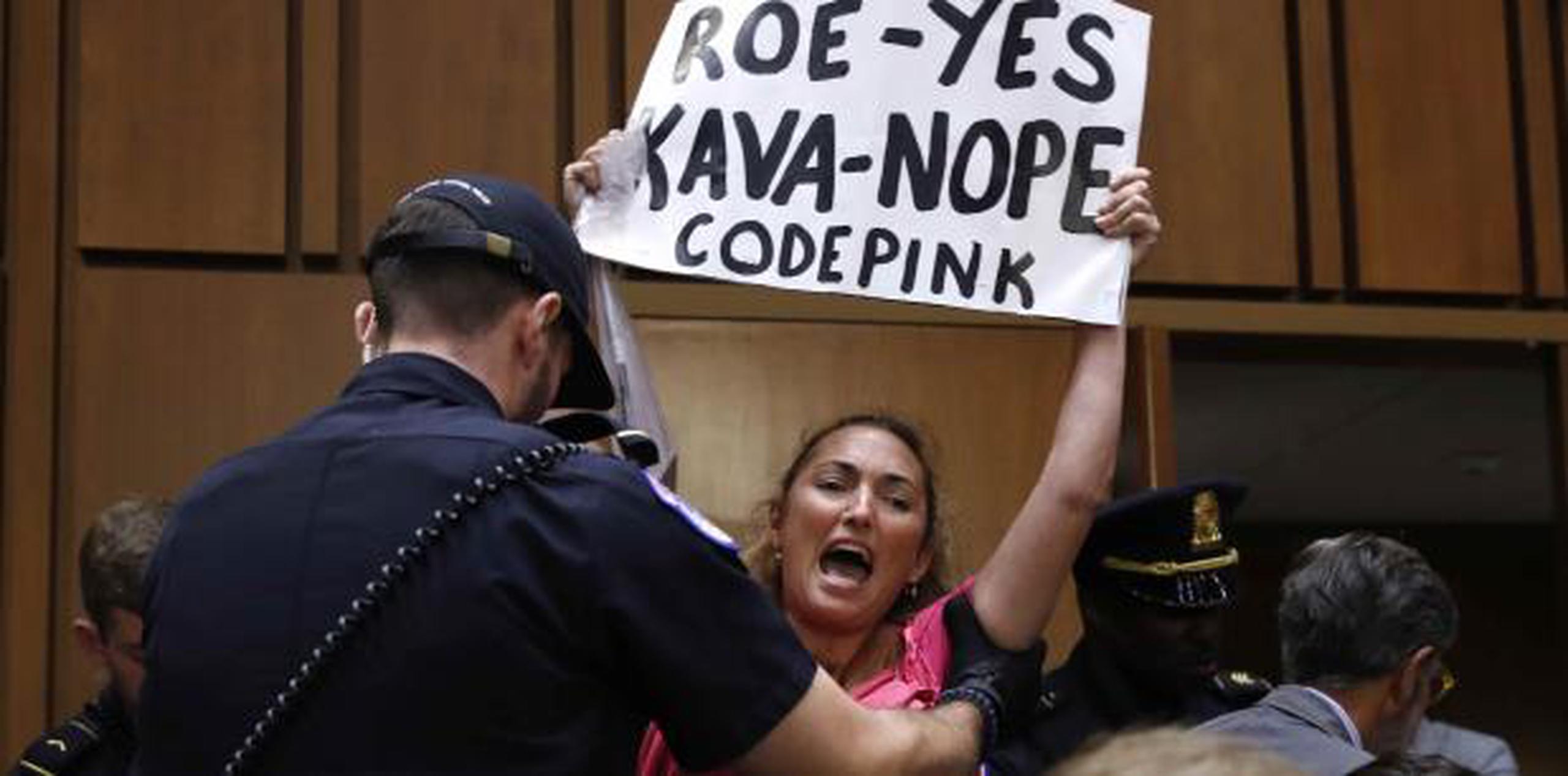 Una manifestante con una pancarta alusiva al caso que legaliza el aborto "Roe vs Wade" es sacada del salón de audiencias por personal de seguridad del Congreso. (AP)