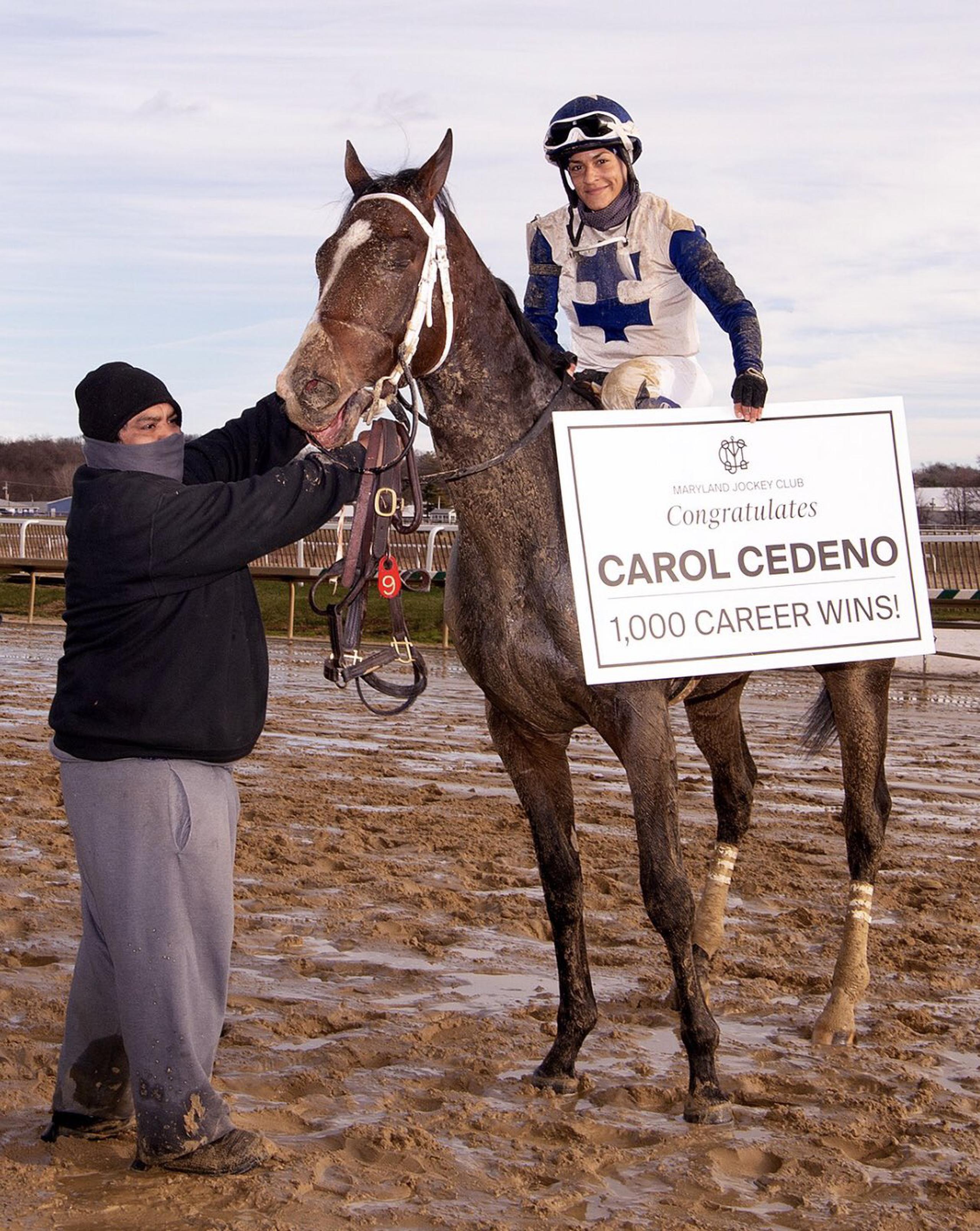 Carol Cedeño muestra el cartel de celebración de los 1,000 triunfos que le hizo el Maryland Jockey Club.