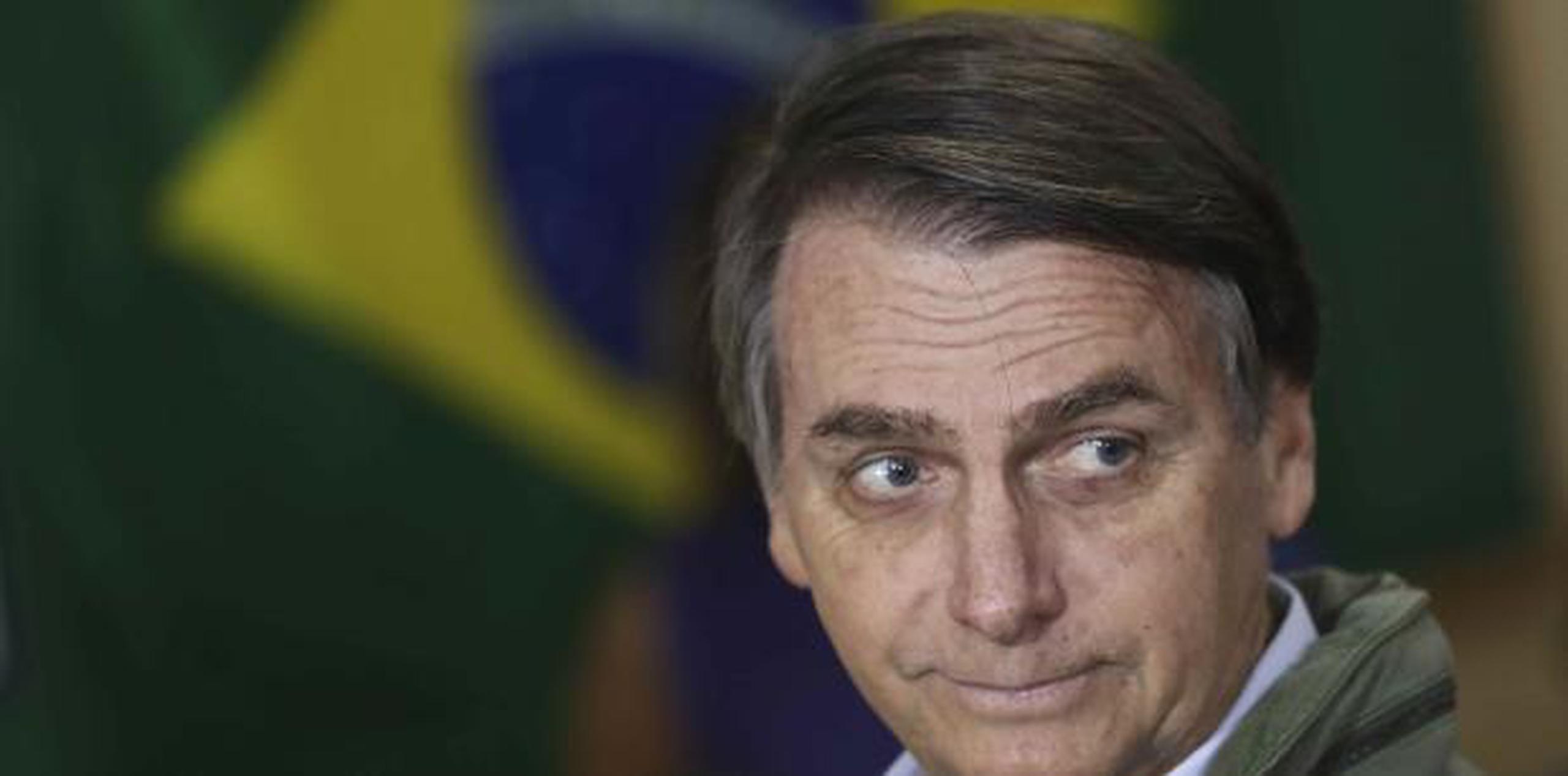 Bolsonaro, aquí con la bandera de Brasil al fondo,  ganó a pesar des us radicales posturas y su renuencia a debatir con su rival por "razones médicas". (AP)