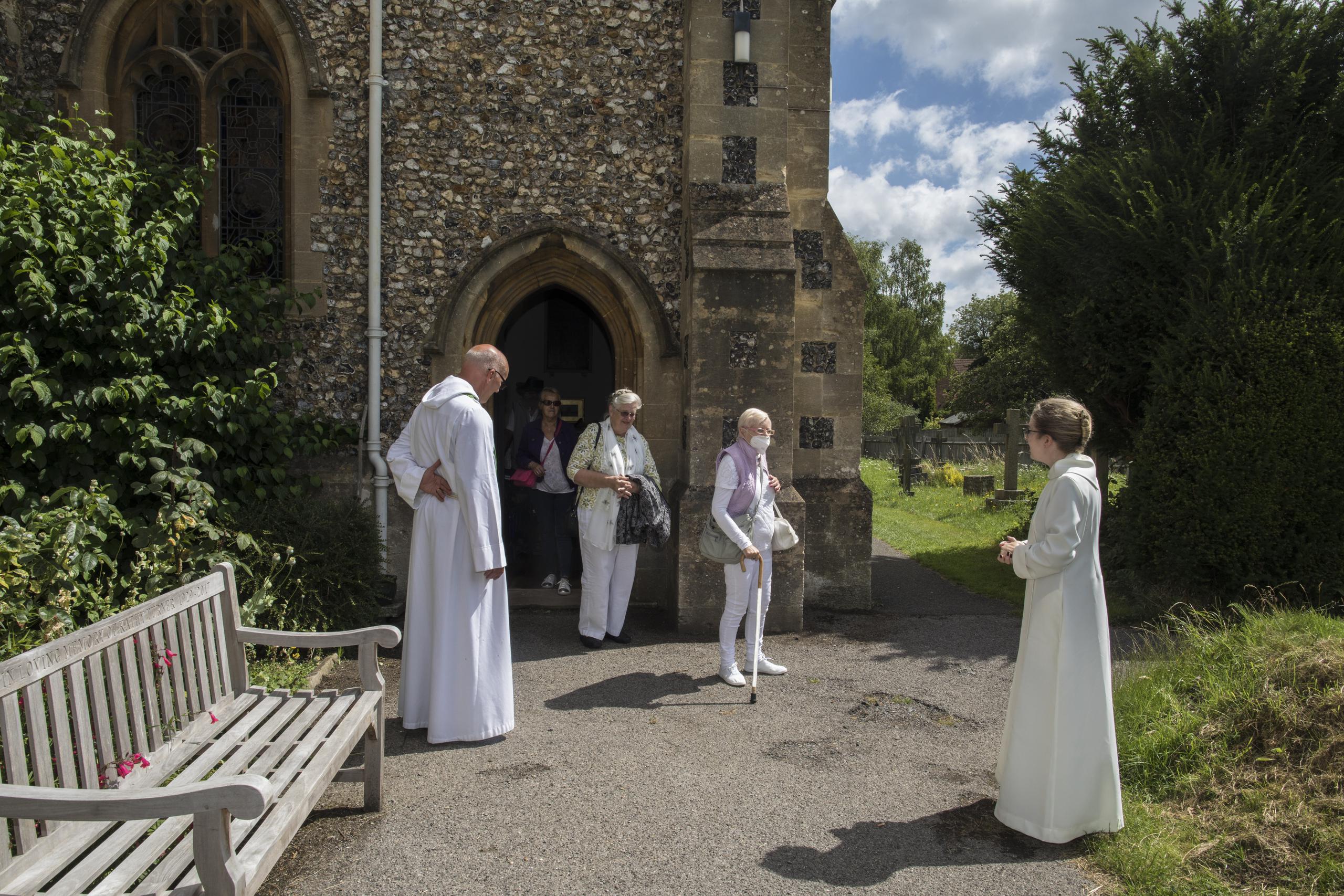 El reverendo Jonathan Gordon, izquierda, y la vicaria adjunta Miranda Shelton reciben a feligreses anglicanos en su primer oficio comunitario al mitigarse la cuarentena de la pandemia en la igleia de Santa María en Northchurch in Berkhamsted, Inglaterra