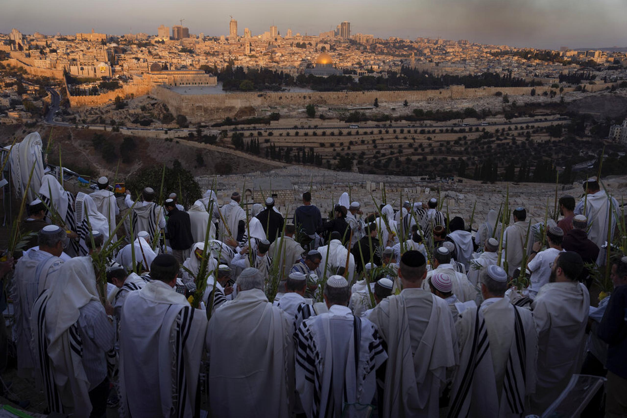 Judíos ultraortodoxos realizan la oración Hoshana Rabbah el séptimo día de la festividad judía de Sukkot en el Monte de los Olivos con vista a la Ciudad Vieja de Jerusalén, el 16 de octubre de 2022.