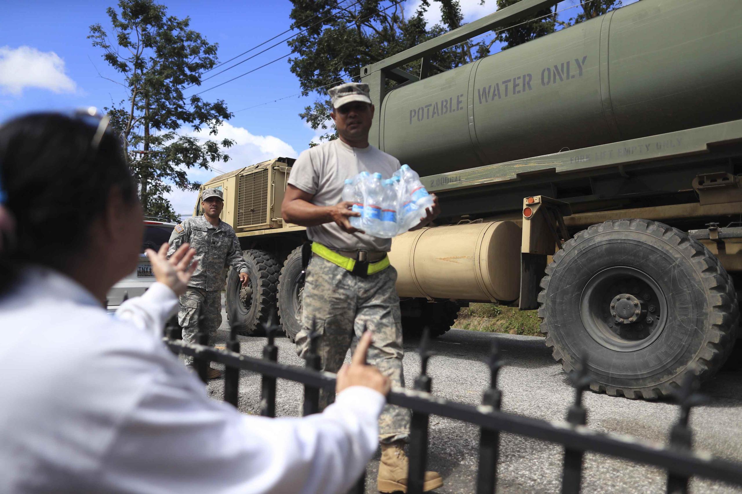 Lugo y su familia no cuentan con servicio de electricidad ni agua potable desde el paso de María el 20 de septiembre de 2017. Un soldado de la Guardia Nacional le entrega a Lugo botellas de agua.