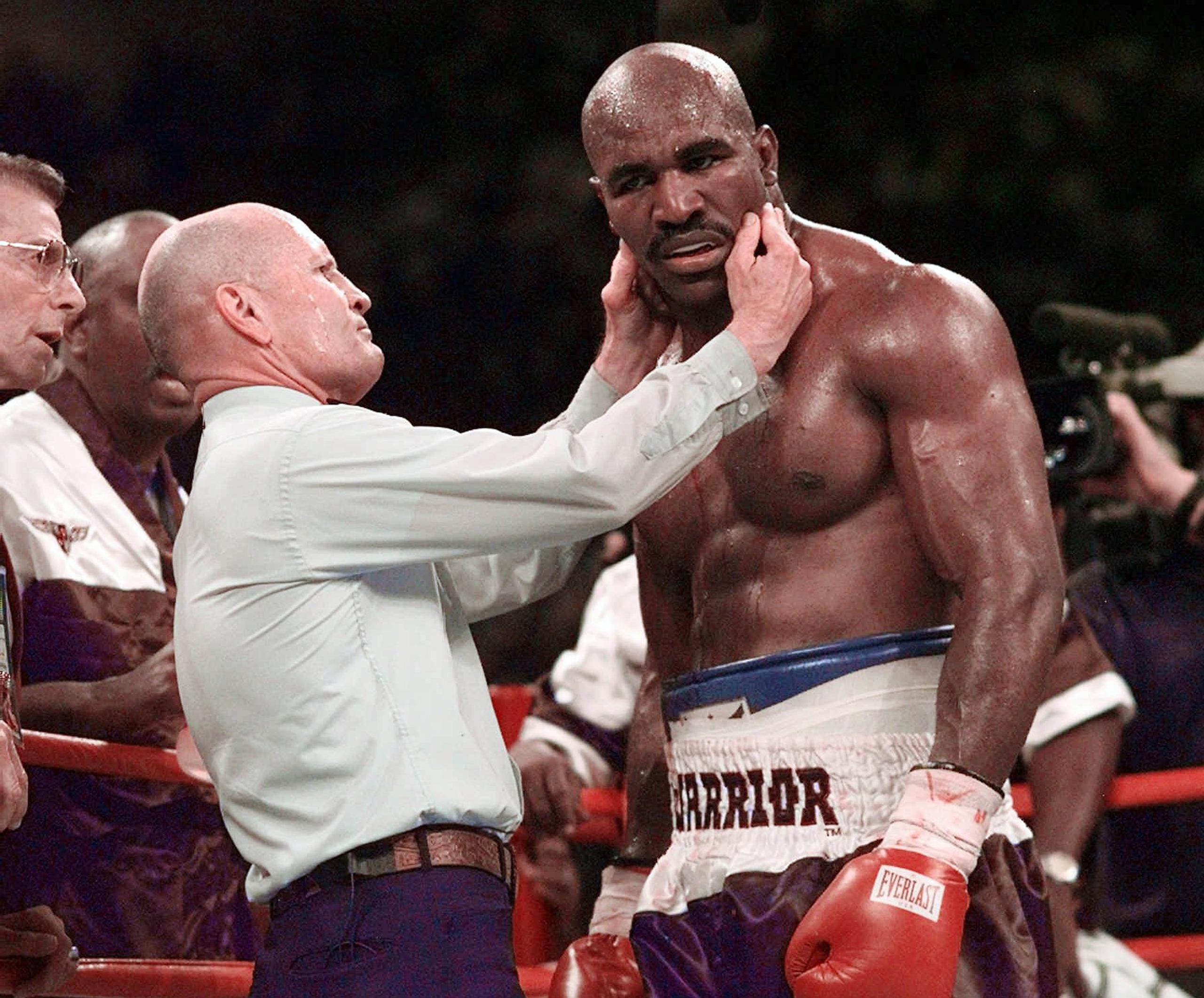 El árbitro Mills Lane revisa a Evander Holyfield durante el infame combate en que Mike Tyson le arrancó parte de la oreja con un mordisco en 1997.