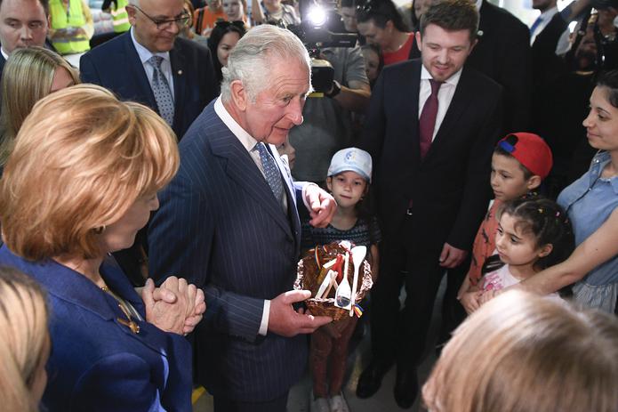 El príncipe Carlos de Gran Bretaña y la princesa Margarita, custodia de la corona rumana, reciben regalos durante una visita a un centro para refugiados de la guerra en Ucrania en el centro de convenciones Romexpo en Bucarest, Rumania, el 25 de mayo de 2022. (Alex Micsik/Pool via AP)
