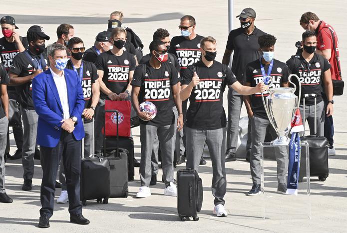 El gobernador de Bavaria Markus Soeder (izquierda) junto al plantel del Bayern Múnich tras su arribo al aeropuerto de Múnich, Alemania, el lunes 24 de agosto de 2020. El arquero Manuel Neuer carga el trofeo de la Liga de Campeones.