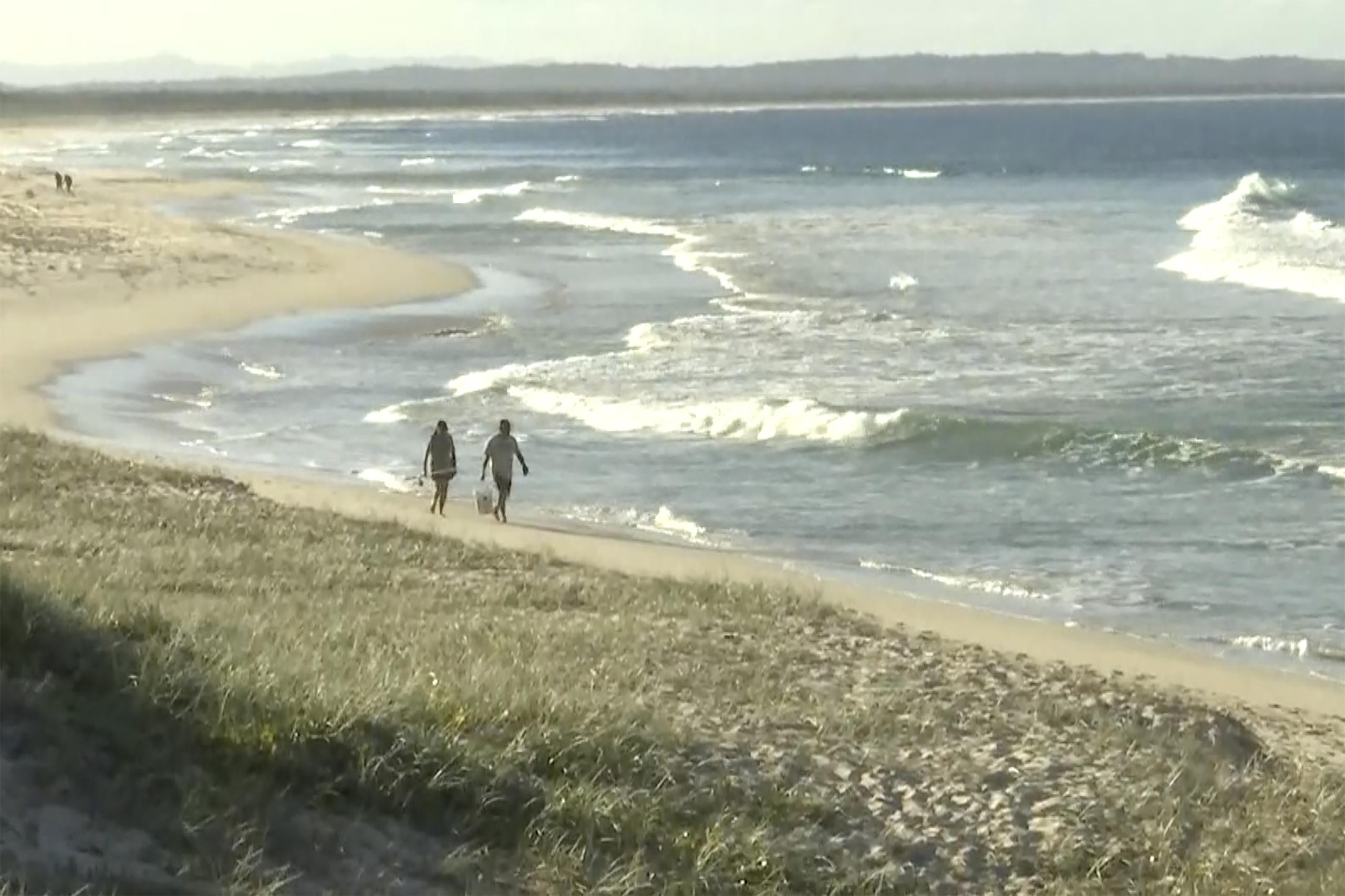 En esta imagen tomada de un video, la gente camina por una playa en Tuncurry, Australia, el 18 de mayo de 2021.