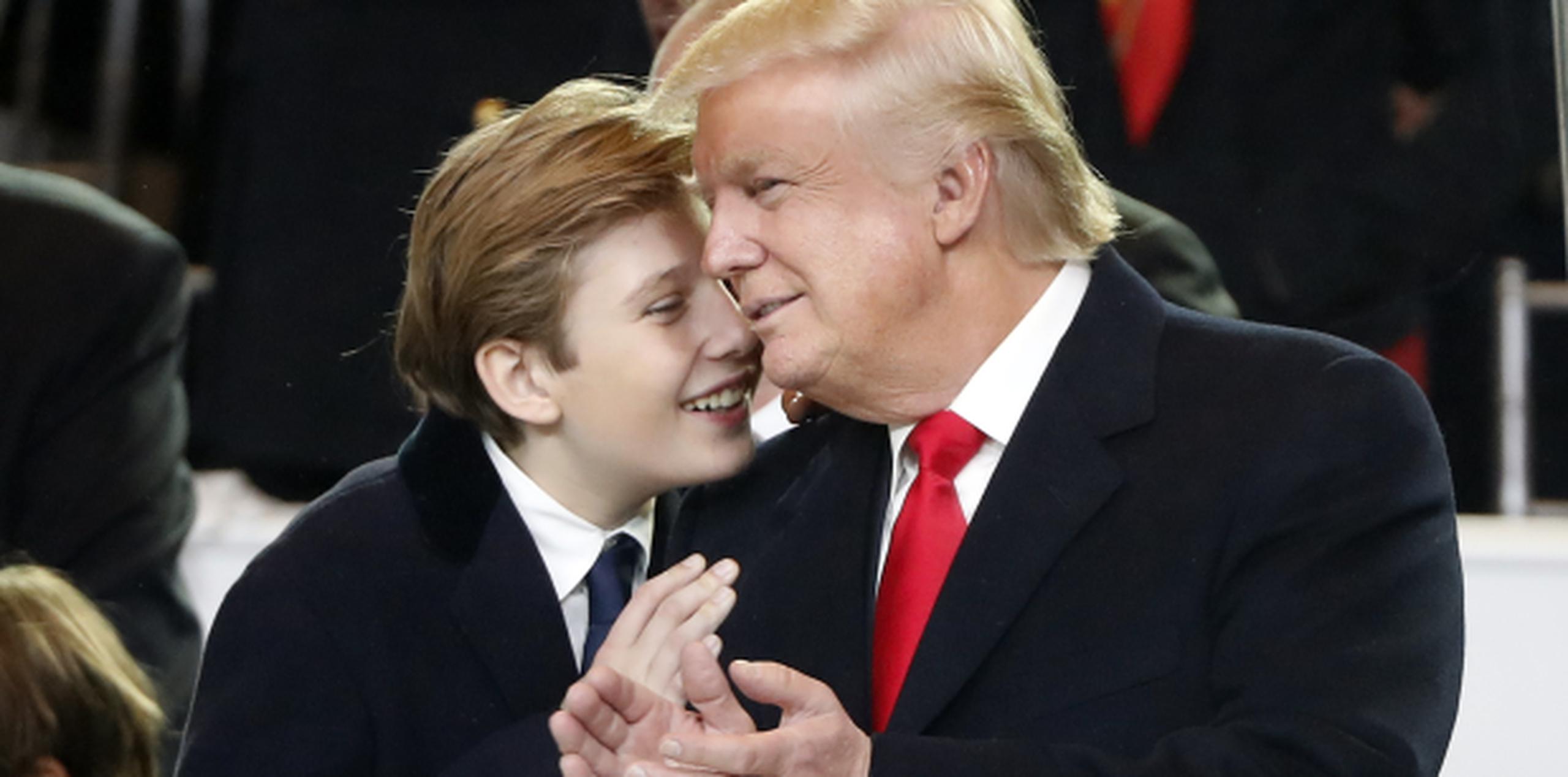 Barron Trump sonríe mientras habla al oído de su padre, el presidente Donald Trump, durante su juramentación. (AP)