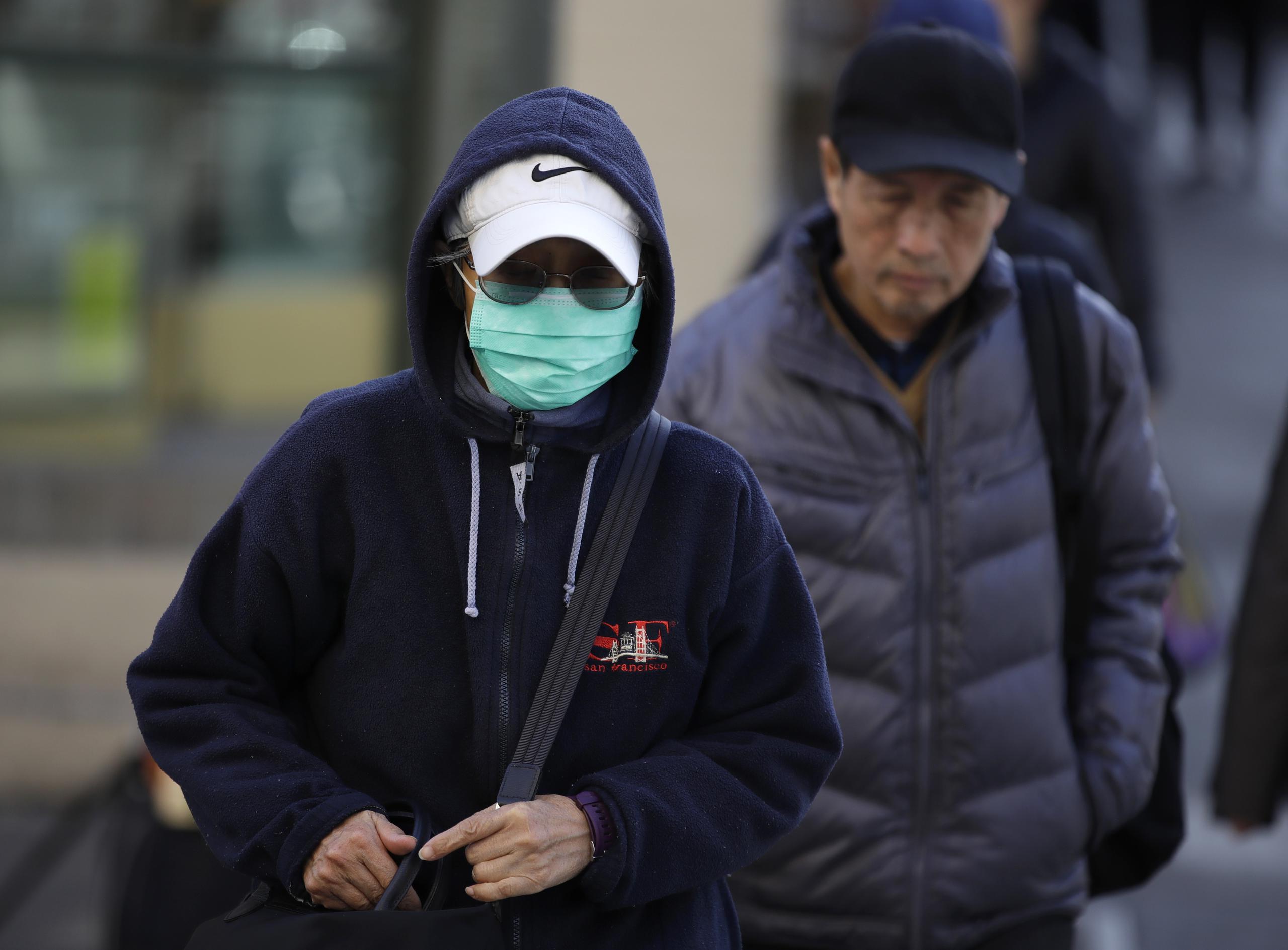 A masked woman walks a street in the Chinatown district of San Francisco on Friday, Jan. 31, 2020. As China grapples with the growing coronavirus outbreak, Chinese people in California are encountering a cultural disconnect as they brace for a possible spread of the virus in their adopted homeland. (AP Photo/Ben Margot)