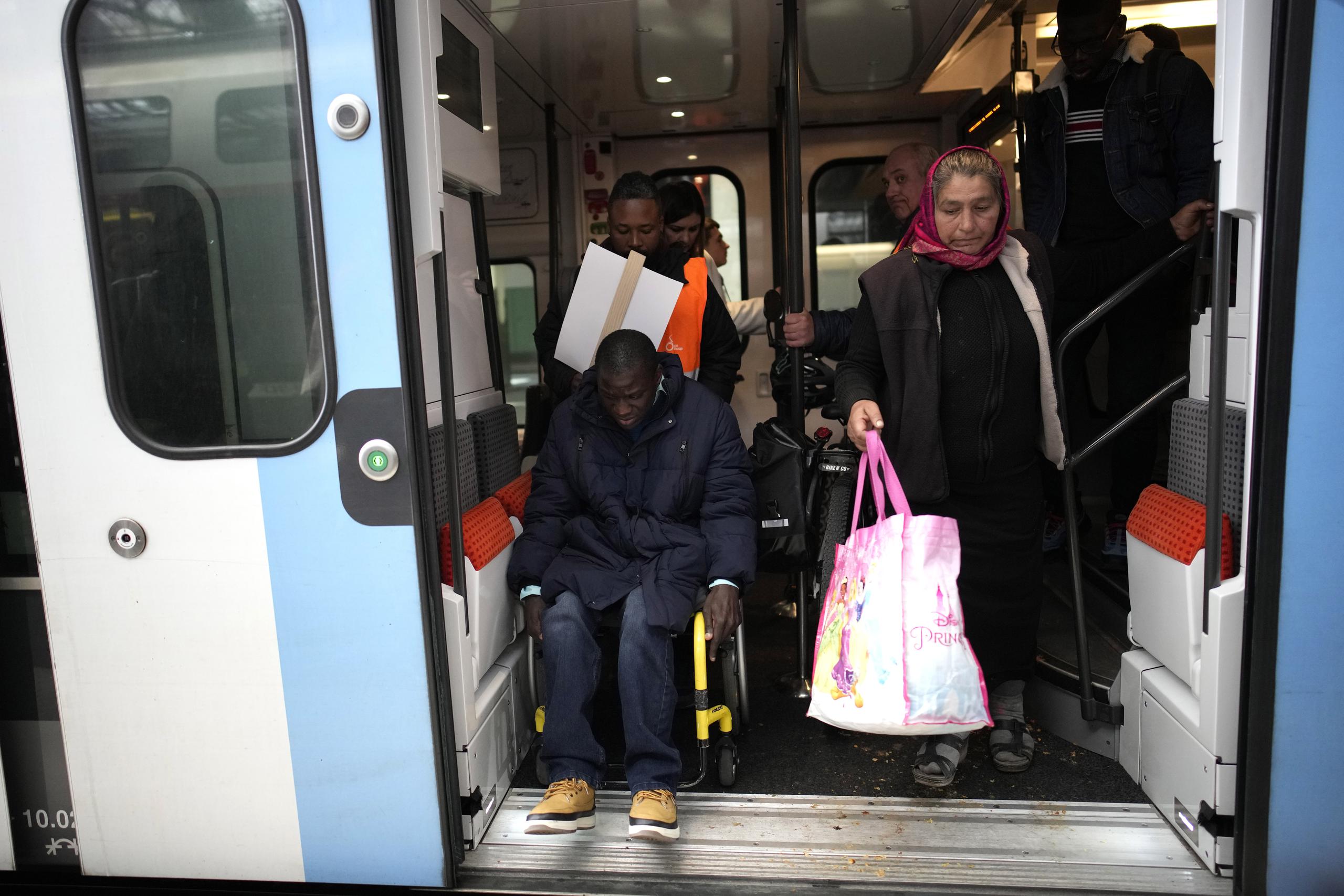ARCHIVO - Babou Sene (izquierda) recibe ayuda al salir de un tren en la Gare de Lyon de París, el miércoles 26 de abril de 2023. (AP Foto/Christophe Ena)
