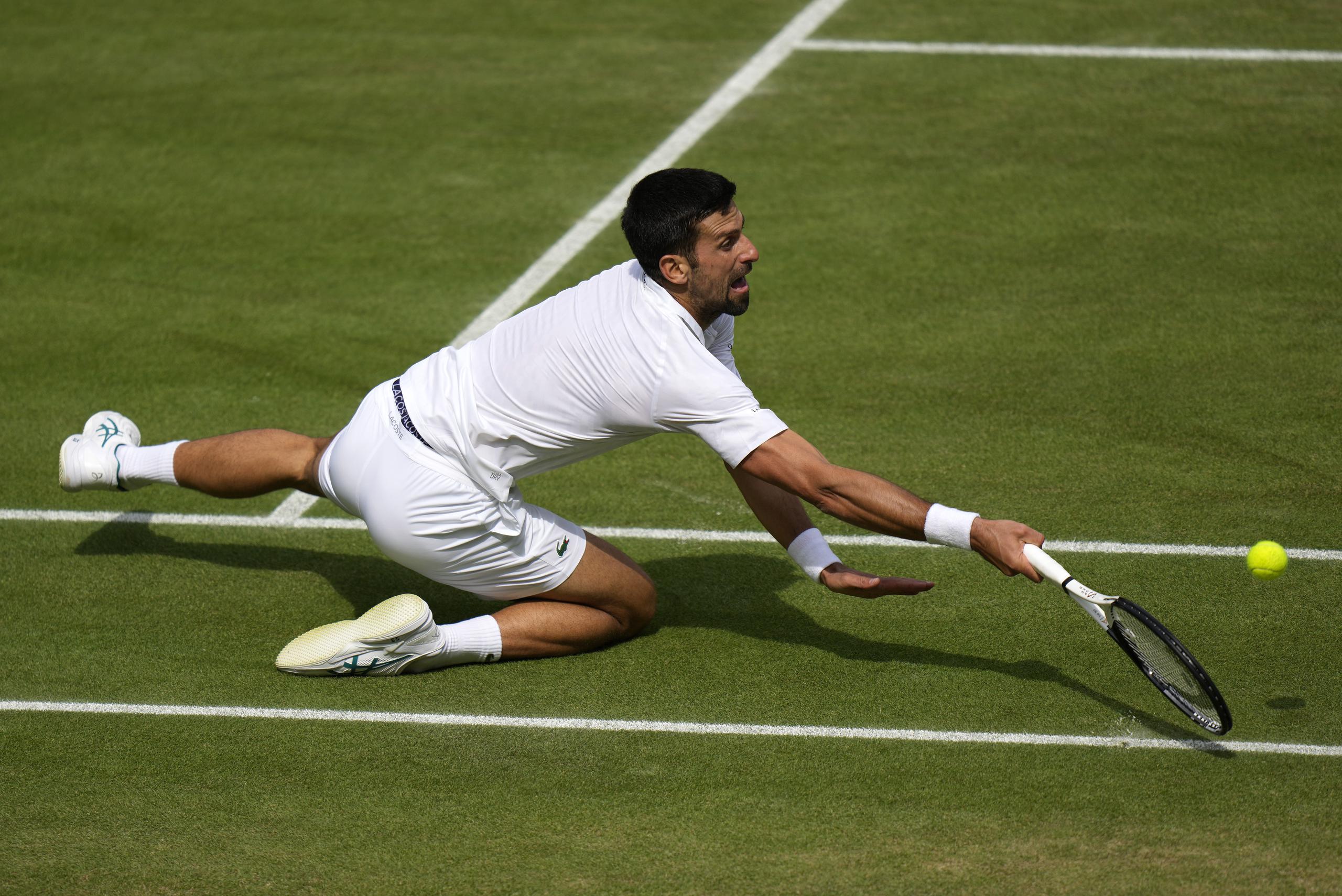 El serbio Novak Djokovic se cae al intentar un derechazo ante el español Carlos Alcaraz en la final masculina de Wimbledon el domingo 16 de julio del 2023. (AP Foto/Alastair Grant)