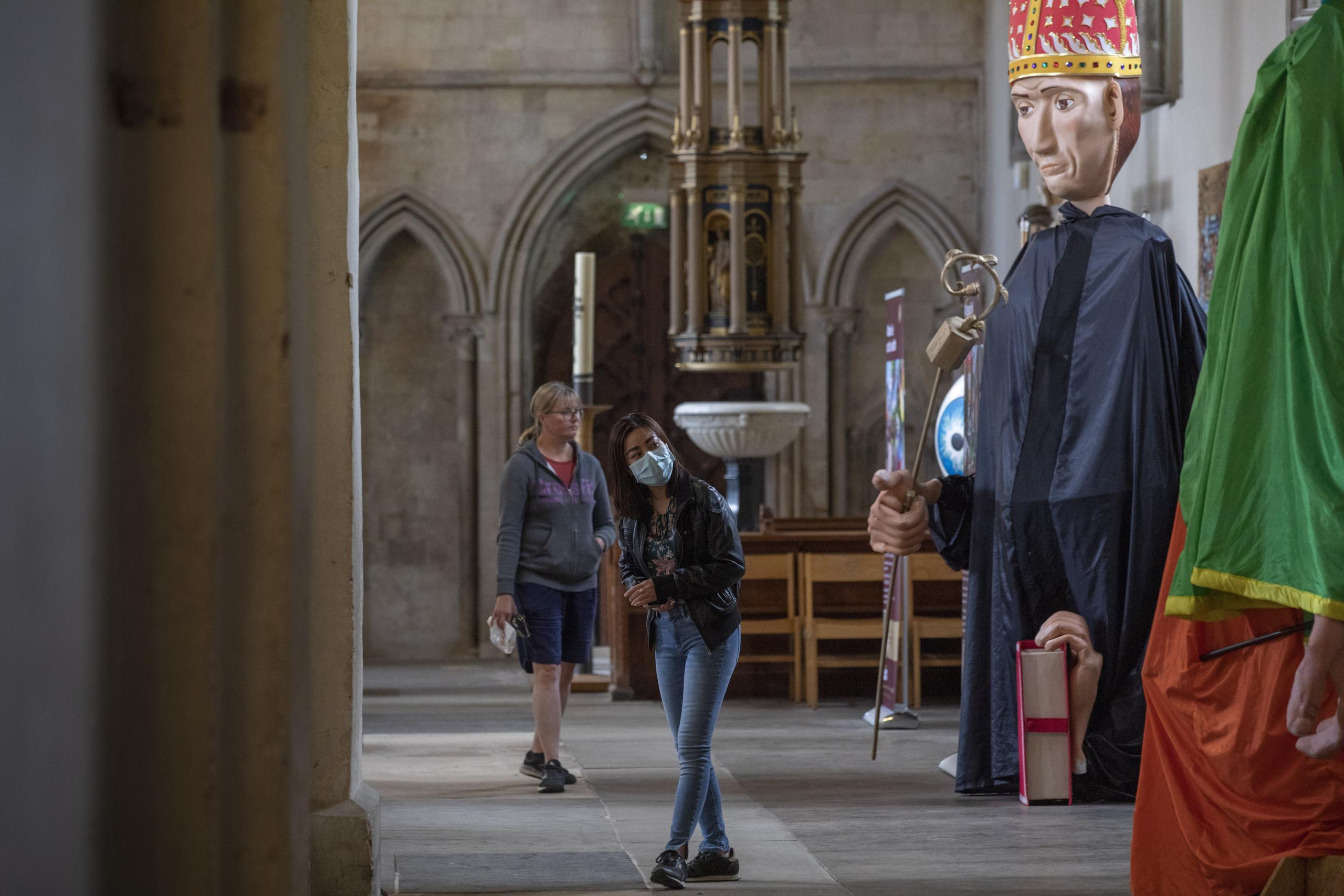 Gente contempla los títeres gigantes, parte de una peregrinación anual que la pandemia obligó a cancelar, en la catedral de St. Albans, Inglaterra