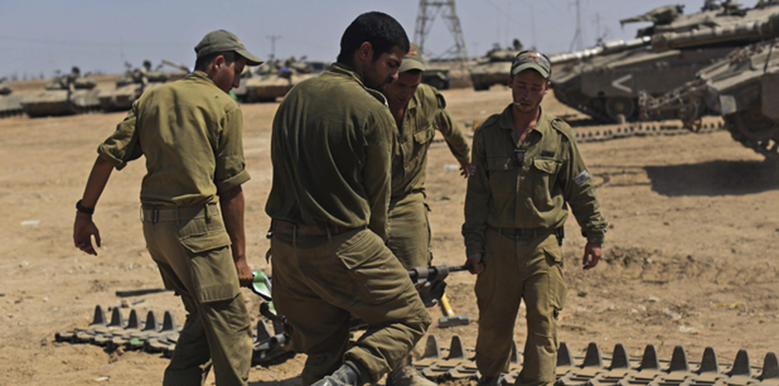 Soldados israelíes llevan a cabo el mantenimiento de la oruga de un carro de combate en un lugar sin especificar en la frontera con la Franja de Gaza. (EFE/Atef Safadi)
