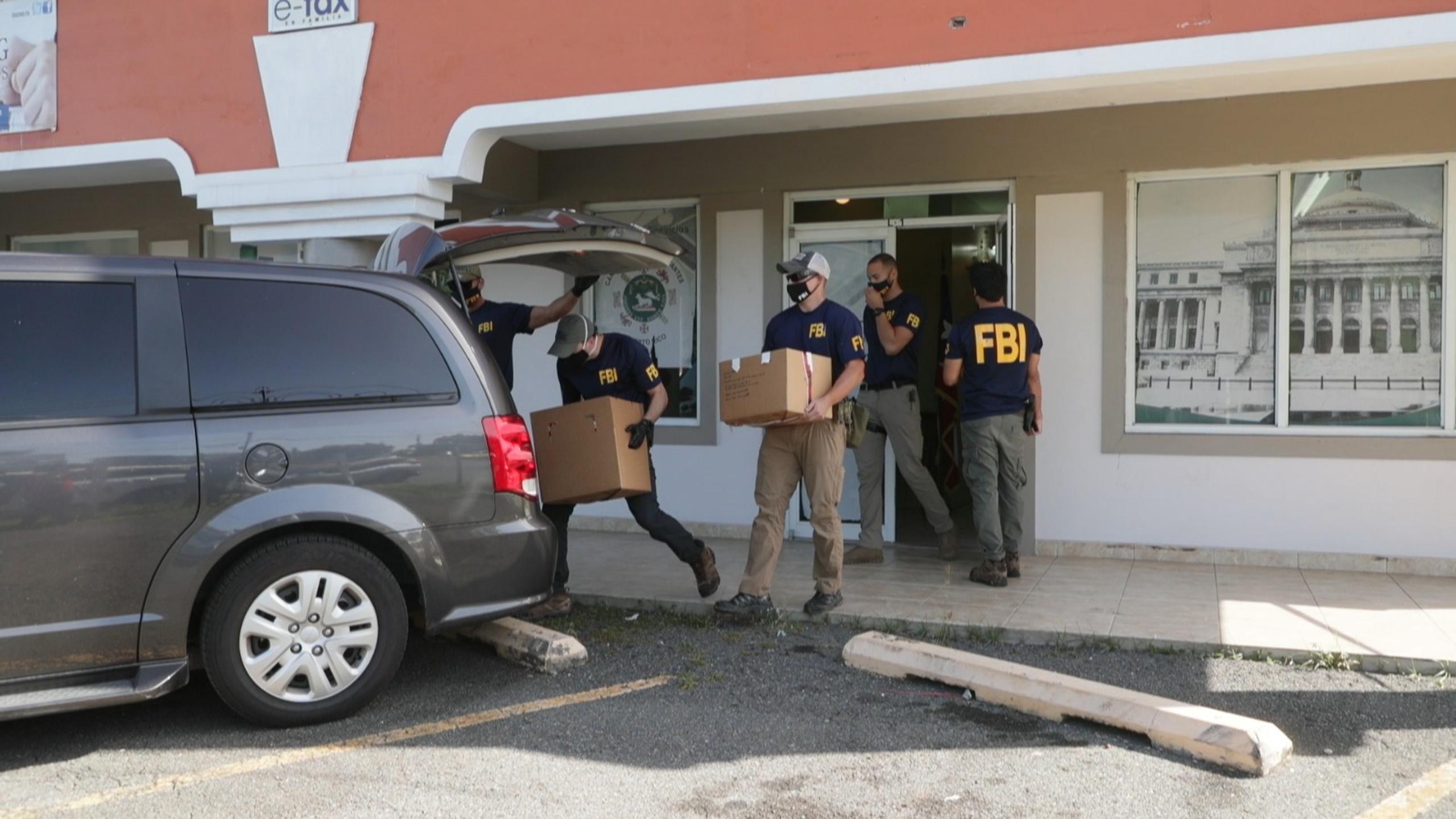 Agentes del FBI cargan con cajas de pertenencias que sacaron de la oficina del representante Nelson del Valle en el barrio Piña, en Toa Alta.