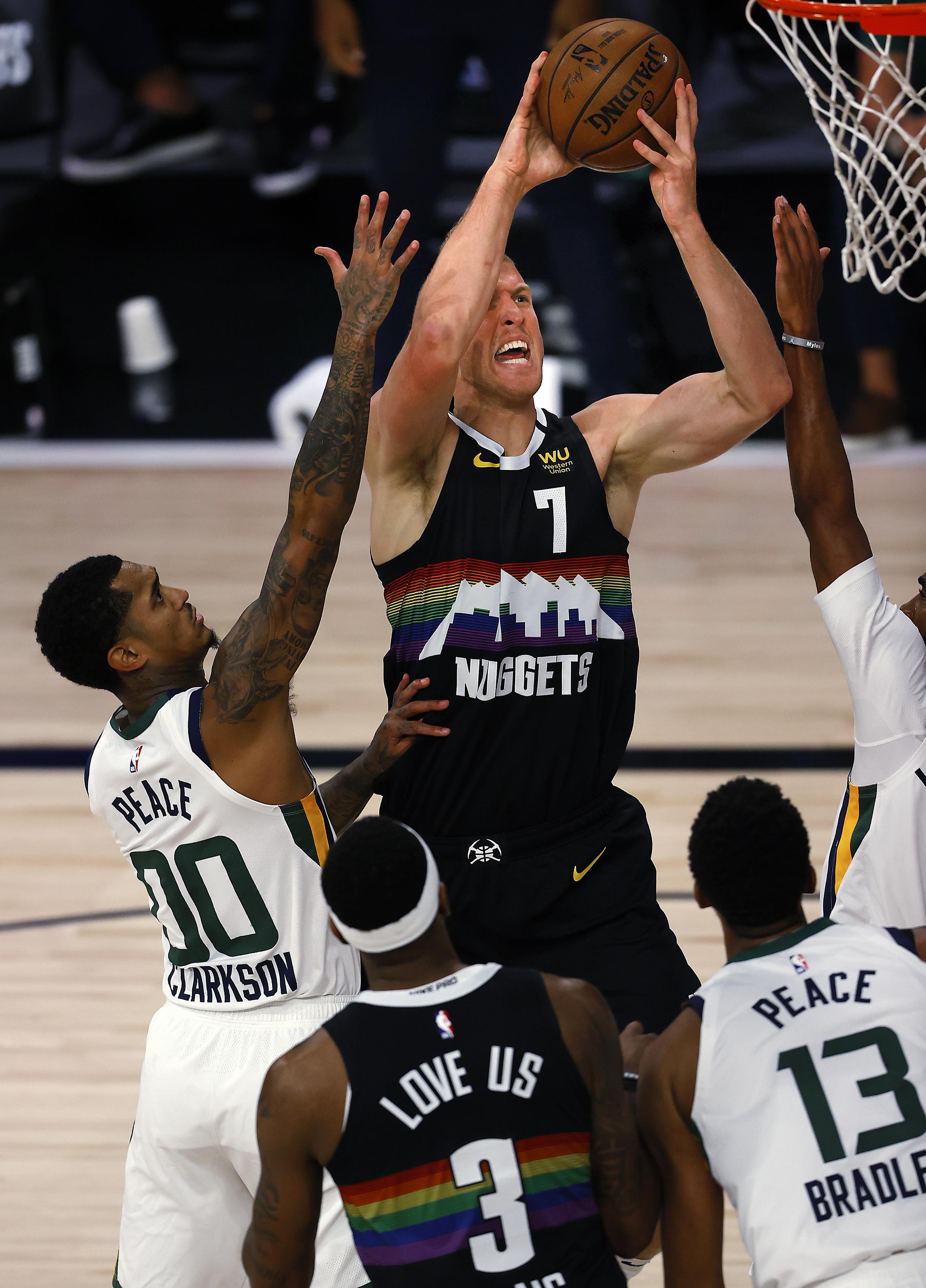 Mason Plumlee, de los Nuggets de Denver, se levanta para realizar un intento contra la defensa de varios jugadores del Jazz de Utah.
