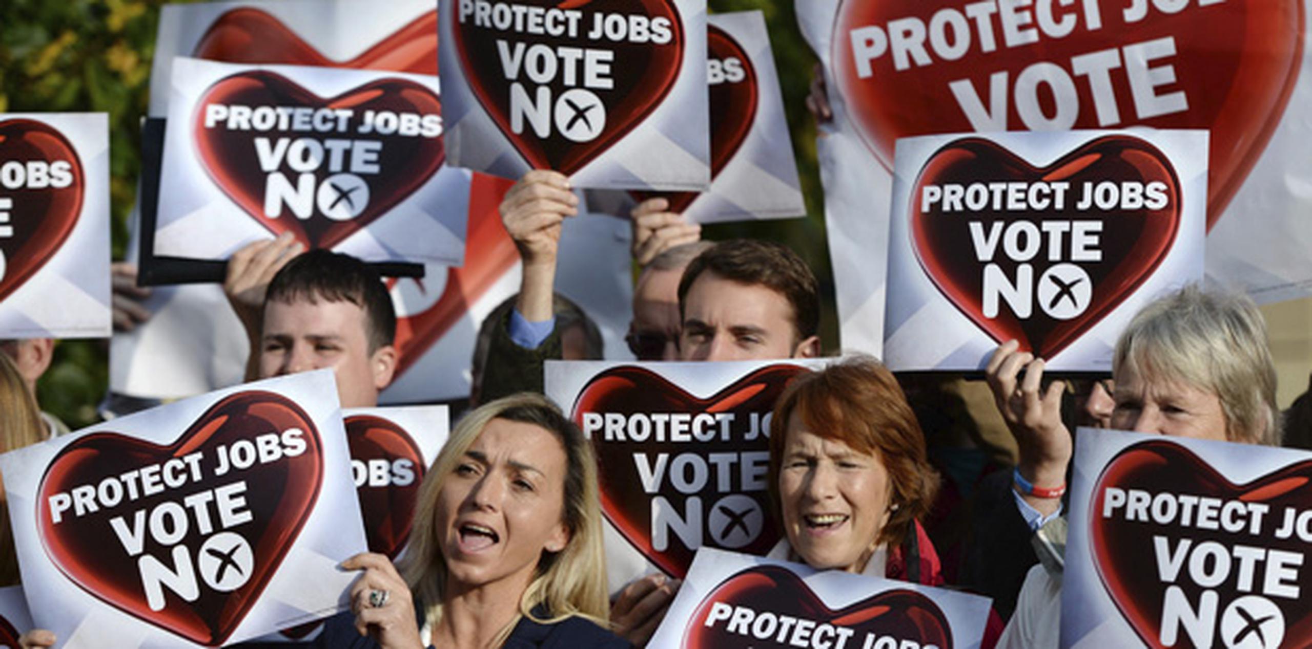 Partidarios del "No" a la independencia sujetan carteles con el mensaje "Protege nuestros trabajos, vota no" en un acto de campaña celebrado en Glasgow. (EFE/Andy Rain)
