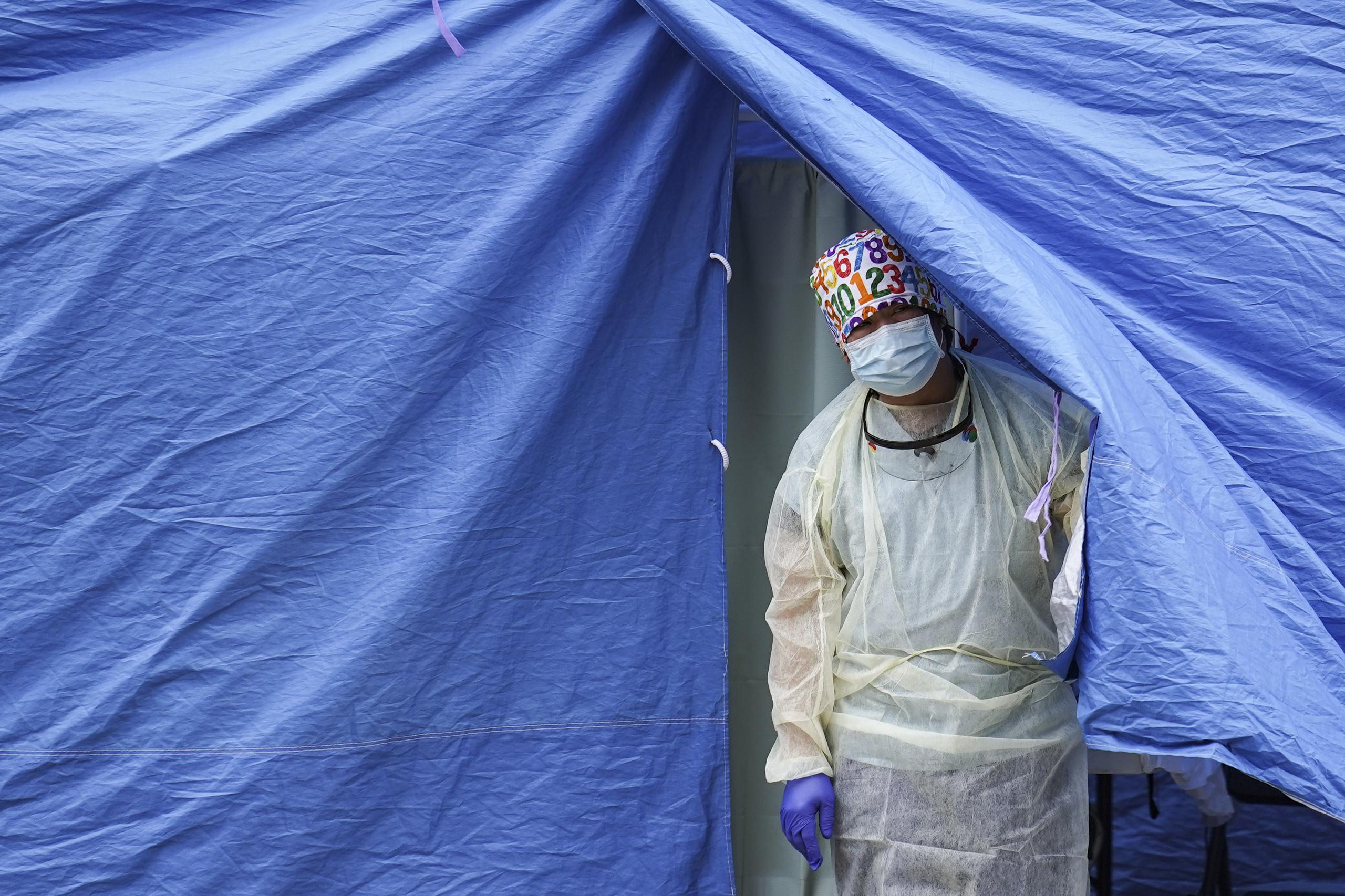 Un trabajador médico sale de una carpa en un sitio de pruebas de COVID-19. (AP Foto/John Minchillo)