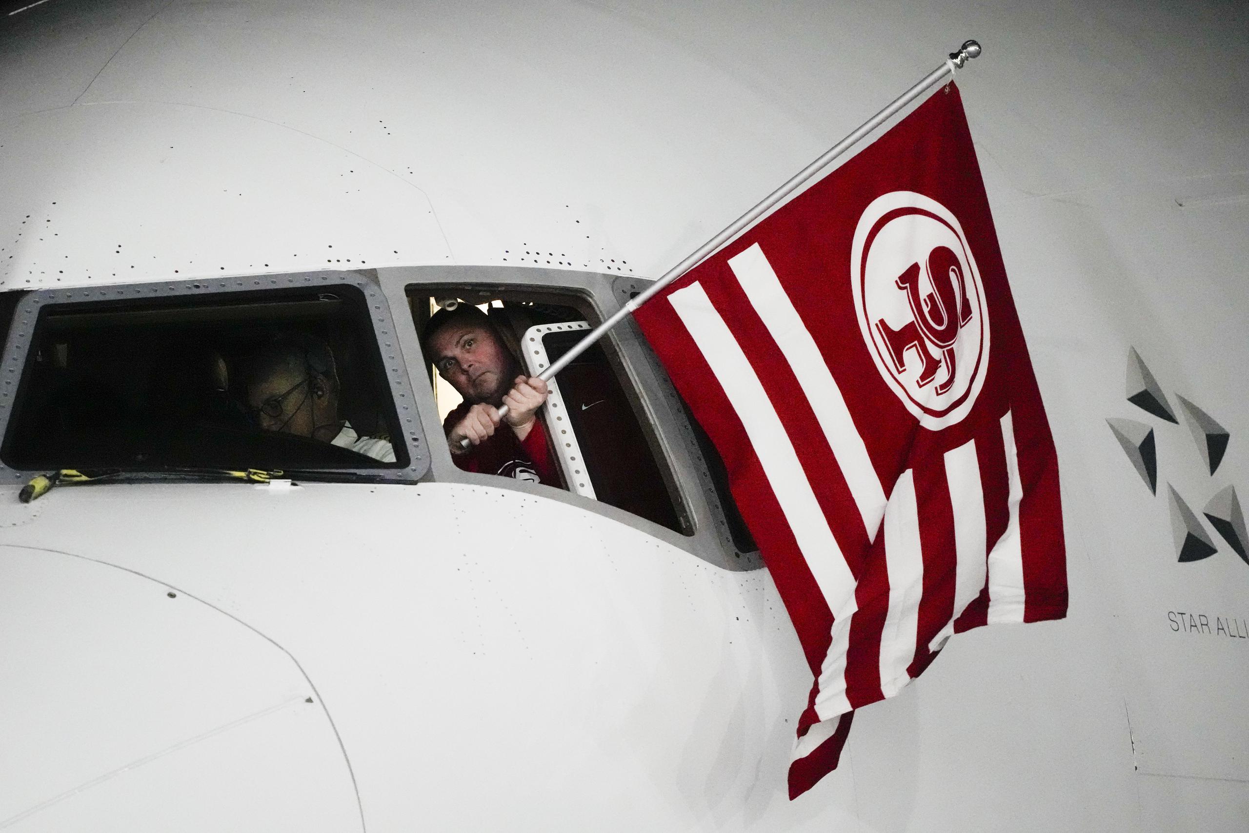 Un miembro de la tripulación que transportó a los 49ers a Las Vegas saca una bandera del equipo por la ventana de la cabina.
