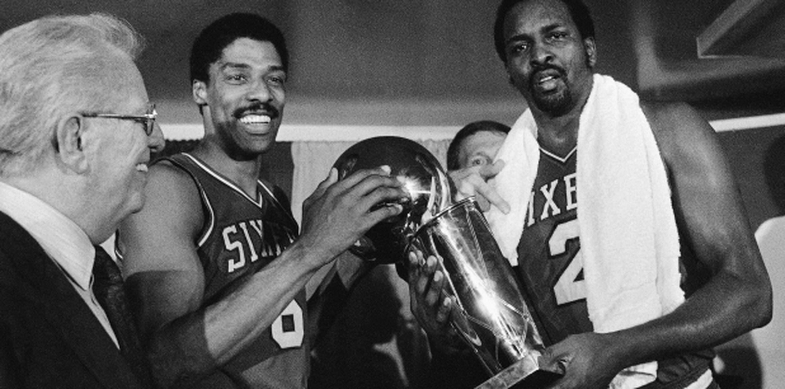 Moses Malone, a la izquierda, comparte con Julius "Dr. J" Erving el trofeo del campeonato que ganaron para Filadelfia en 1983, al derrotar a los Lakers de Los Angeles, que ya contaban en sus filas con Magic Johnson. (AP)
