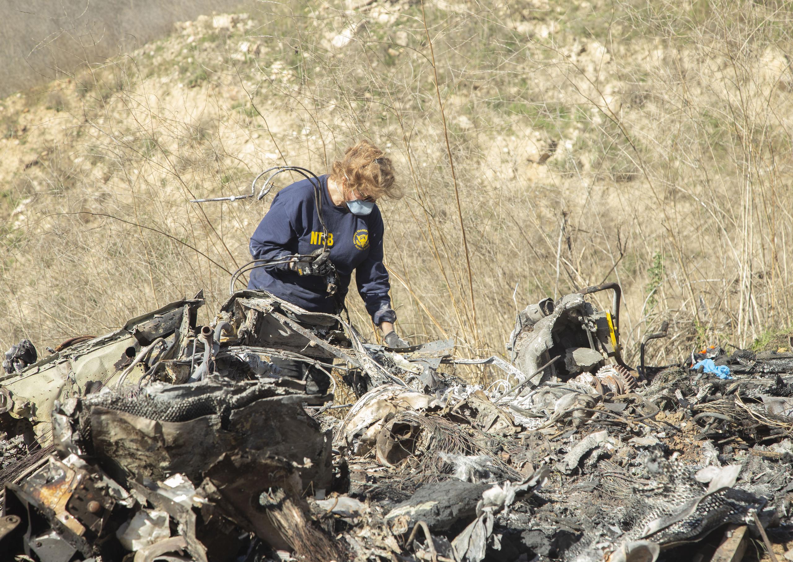 Una investigadora del accidente en el que murió Kobe Bryant, su hija y otras siete personas, examina los restos del helicóptero accidentado.