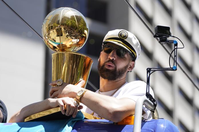 Klay Thompson porta una gorra de capitán y sostiene el trofeo de campeones de la NBA, durante el recorrido del desfile de celebración del título de la NBA de los Warriors de Golden State, el lunes 20 de junio de 2022, en San Francisco. (AP Foto/Eric Risberg)